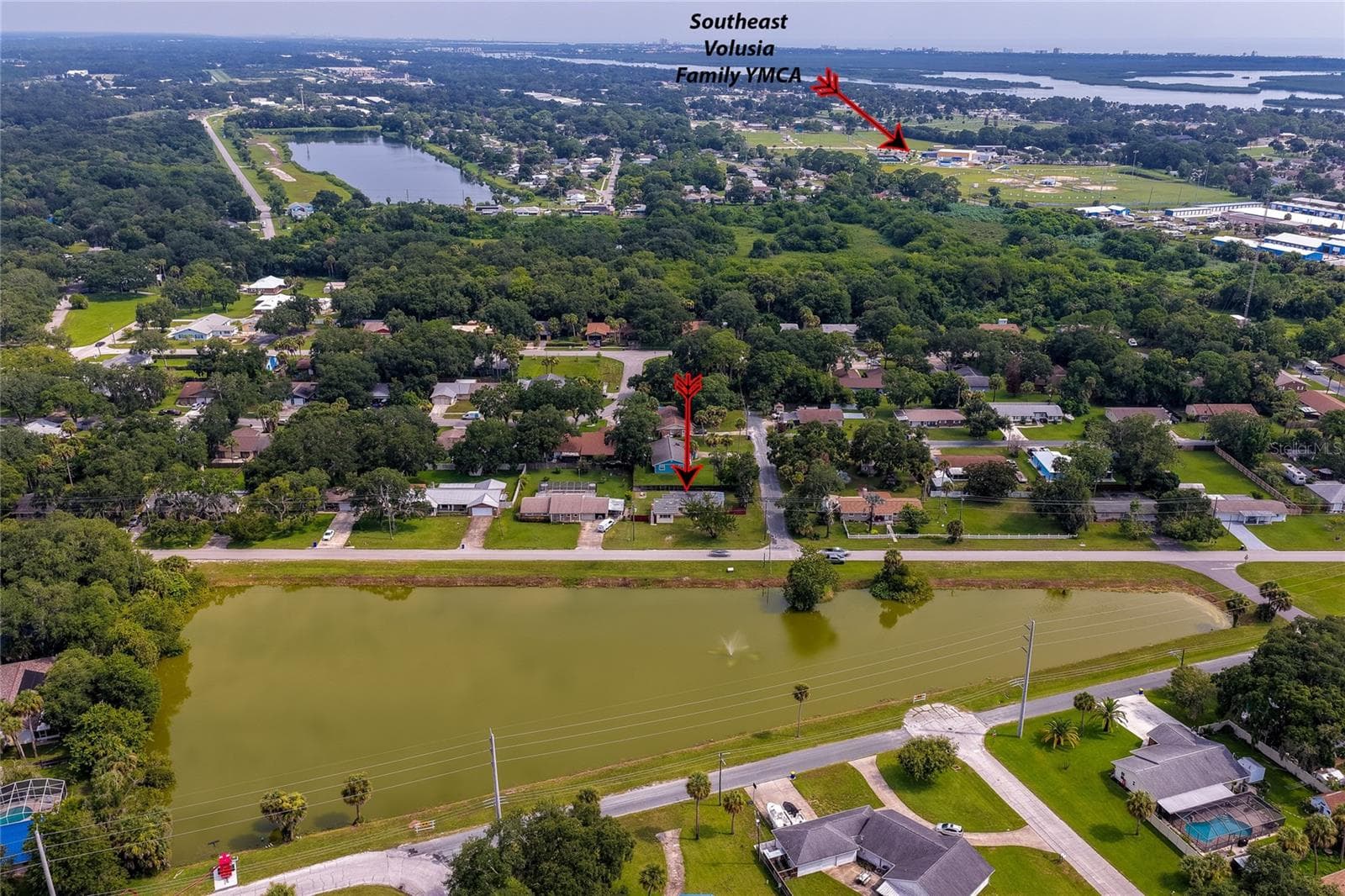 High-altitude aerial photograph highlighting the home's position near the neighborhood pond, surrounding woodland, and proximity to local community amenities. - 1101 16TH ST, EDGEWATER
