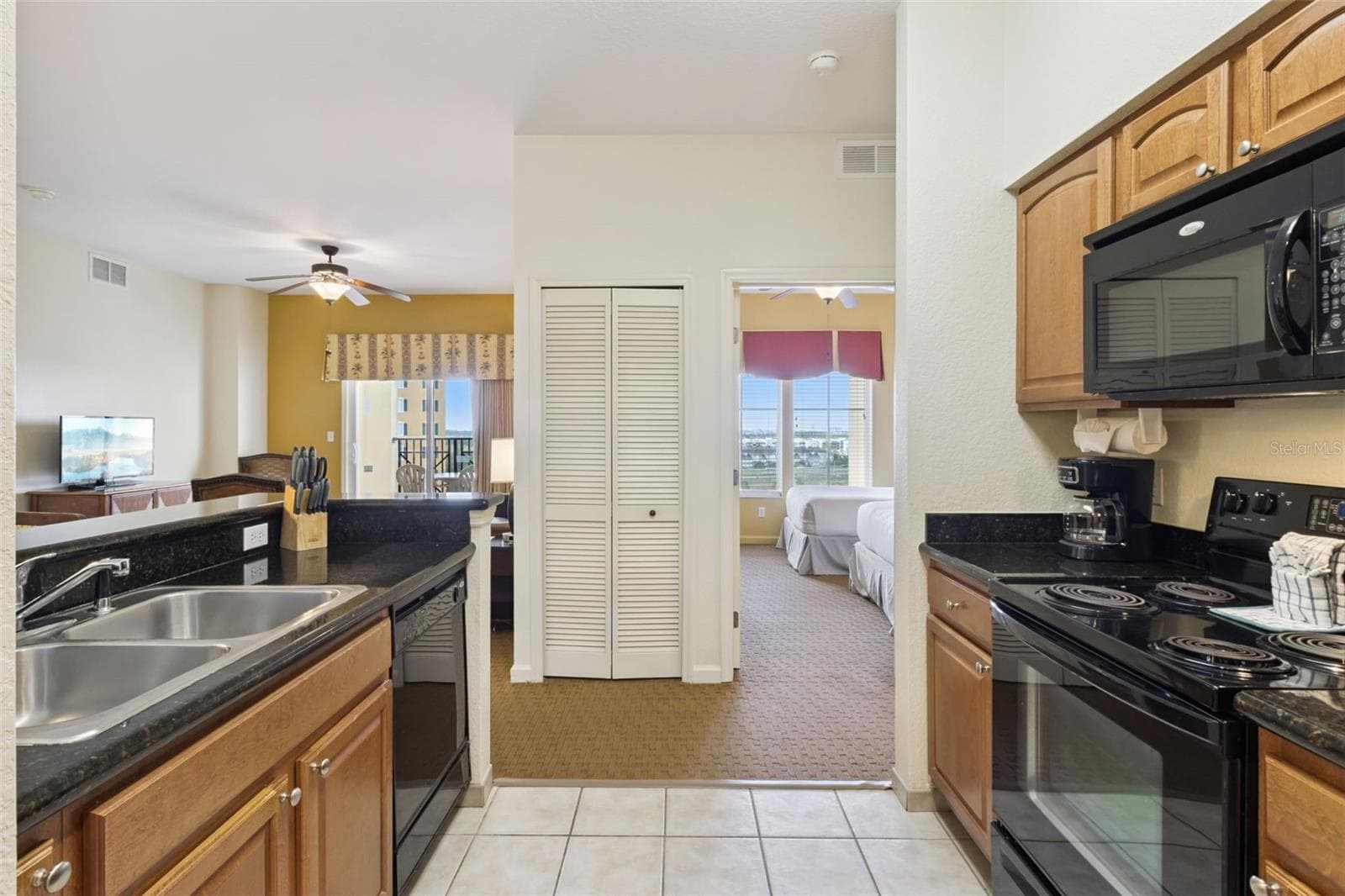 Kitchen and Bedroom Hall | A workspace offers a double-basin sink and convenient access to the 2nd bedroom. - 8101 RESORT VILLAGE DR #31110, ORLANDO