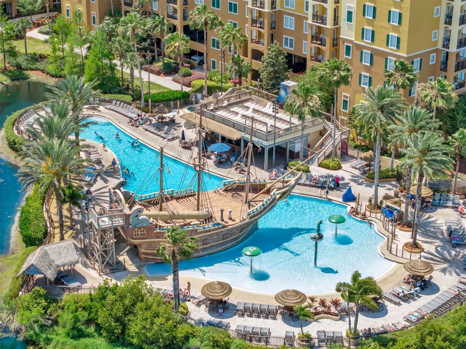 Pool Complex | Aerial views showcase the resort’s tropical pool area, water features, sun deck, and lush landscaping. - 8101 RESORT VILLAGE DR #31110, ORLANDO