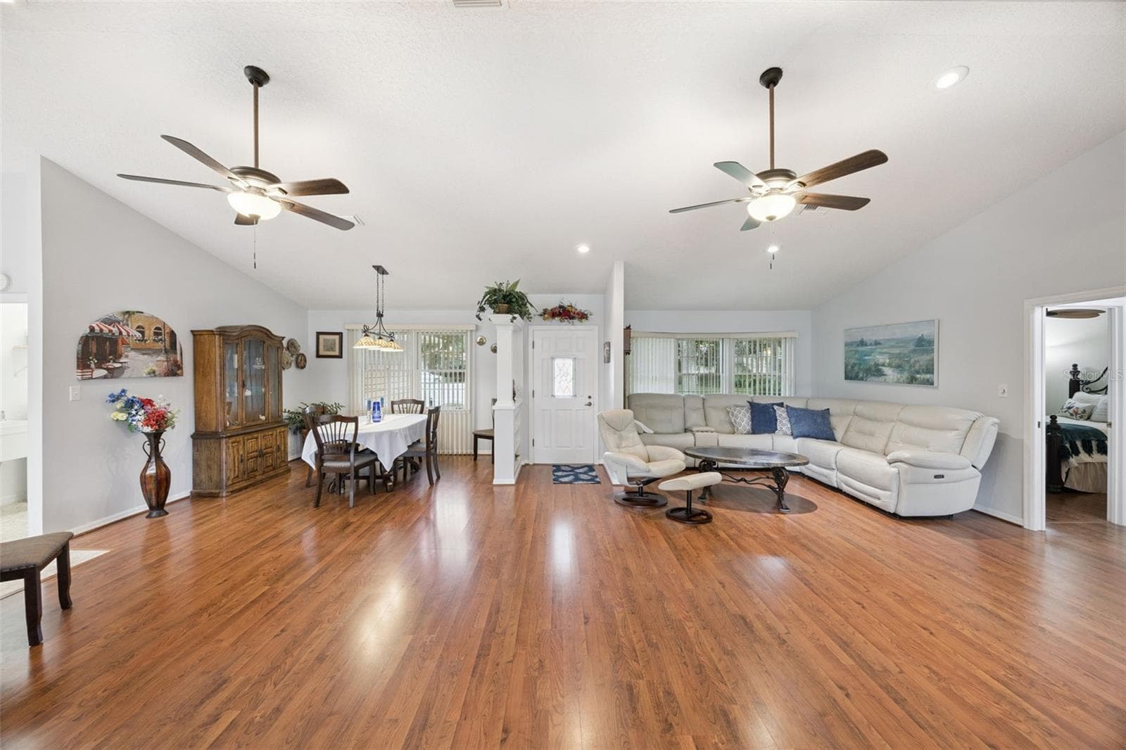 Open-concept great room (21x16) with vaulted ceilings, dual ceiling fans, recessed lighting, and laminate floors at 480 Lake Forest Cir, Mount Dora, FL - 480 LAKE FOREST CIR, MOUNT DORA