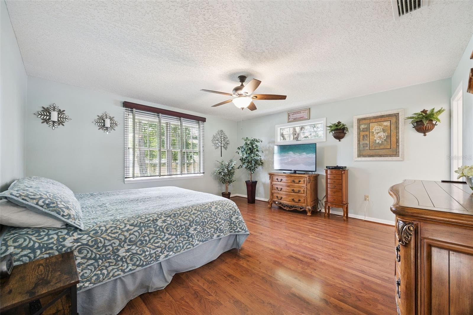 Primary bedroom (15x15) with ceiling fan, laminate floors, and room for king-size furniture in this split-plan home at 480 Lake Forest Cir, Mount Dora - 480 LAKE FOREST CIR, MOUNT DORA