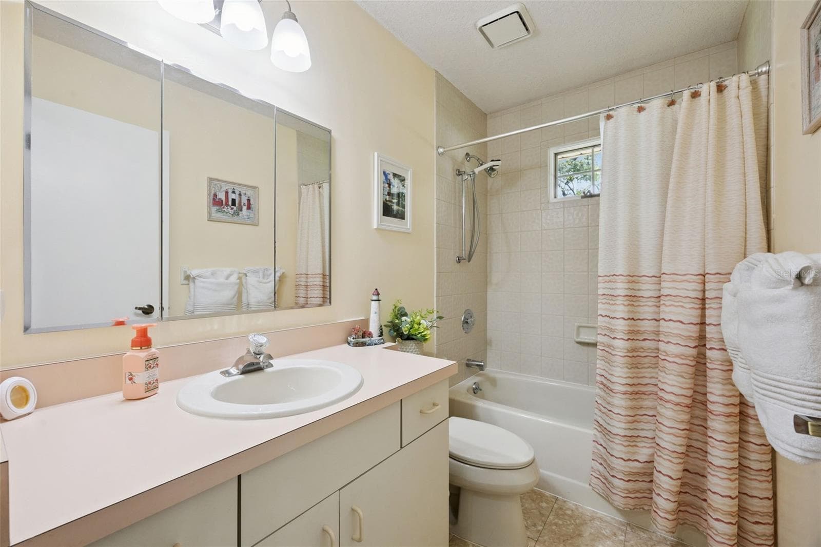 Guest bathroom with vanity, large mirror, and tub/shower combo at 480 Lake Forest Cir, a 2-bath home in Mount Dora's Lake Forest community - 480 LAKE FOREST CIR, MOUNT DORA