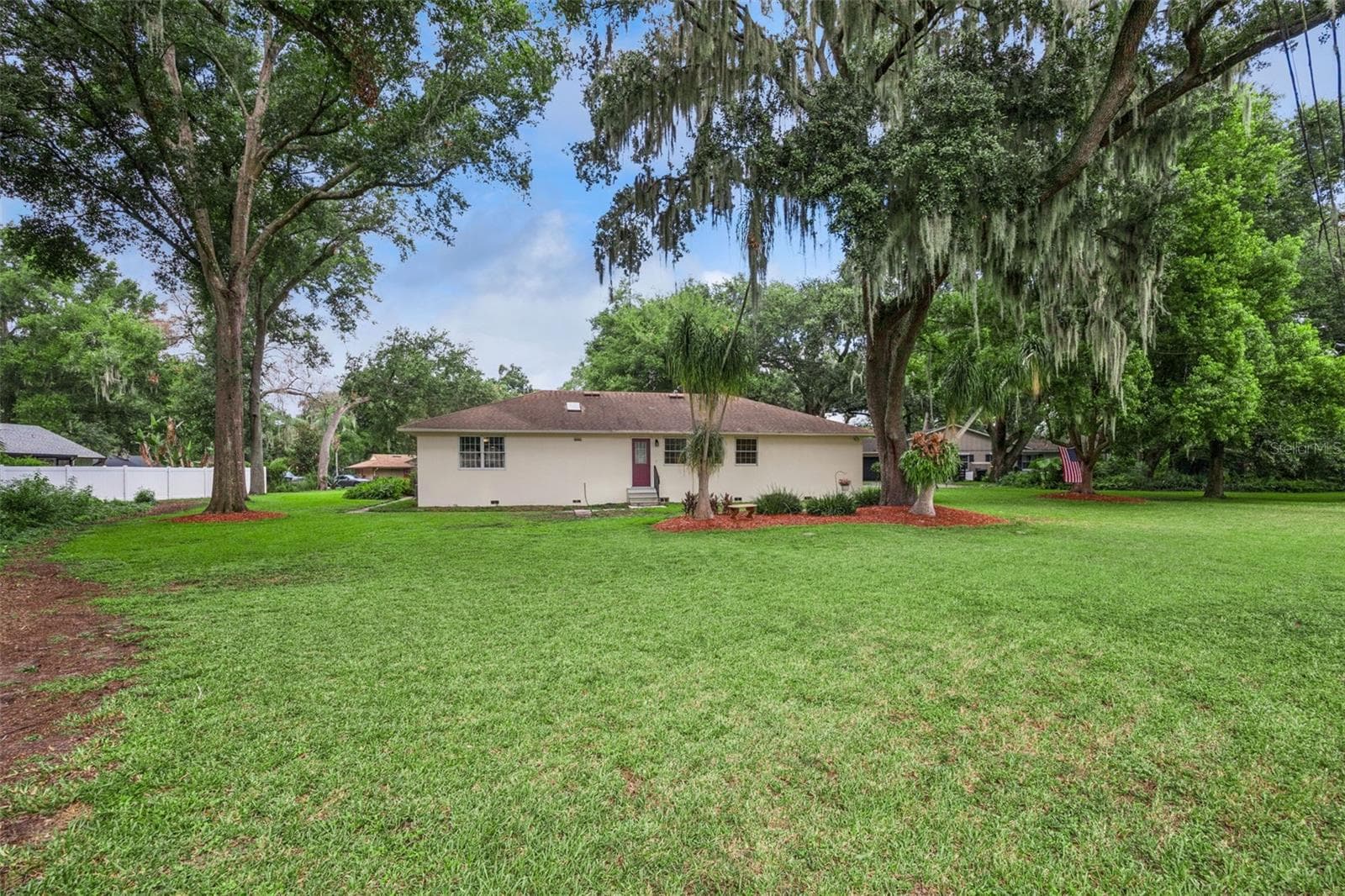 Side yard showing the spacious 112x138 lot with mature landscaping and irrigation system in Mount Dora's Lake Forest neighborhood - 480 LAKE FOREST CIR, MOUNT DORA
