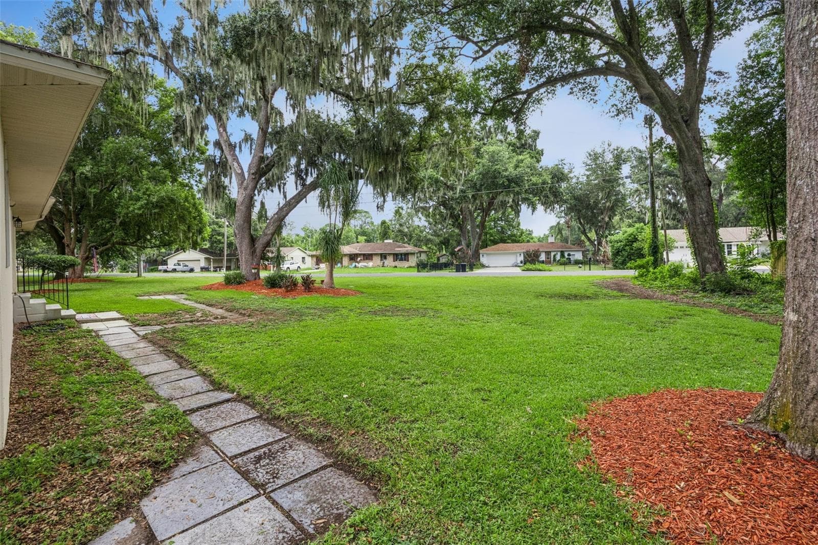 Rear yard through the oak canopy highlighting privacy and generous lot size, minutes from downtown Mount Dora and Lake Dora waterfront - 480 LAKE FOREST CIR, MOUNT DORA