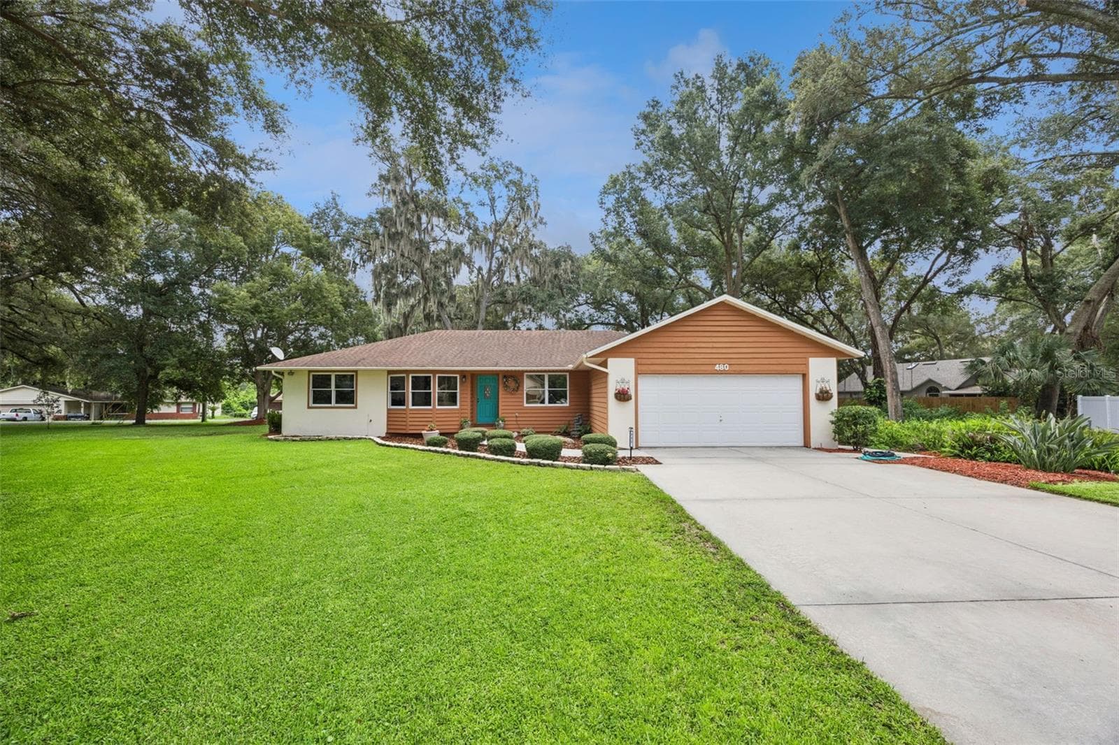 Wide-angle curb appeal view of 480 Lake Forest Cir showing the expansive front yard, 2-car garage, and oak-canopied 0.46-acre lot in Mount Dora's Lake Forest neighborhood, just minutes from downtown - 480 LAKE FOREST CIR, MOUNT DORA