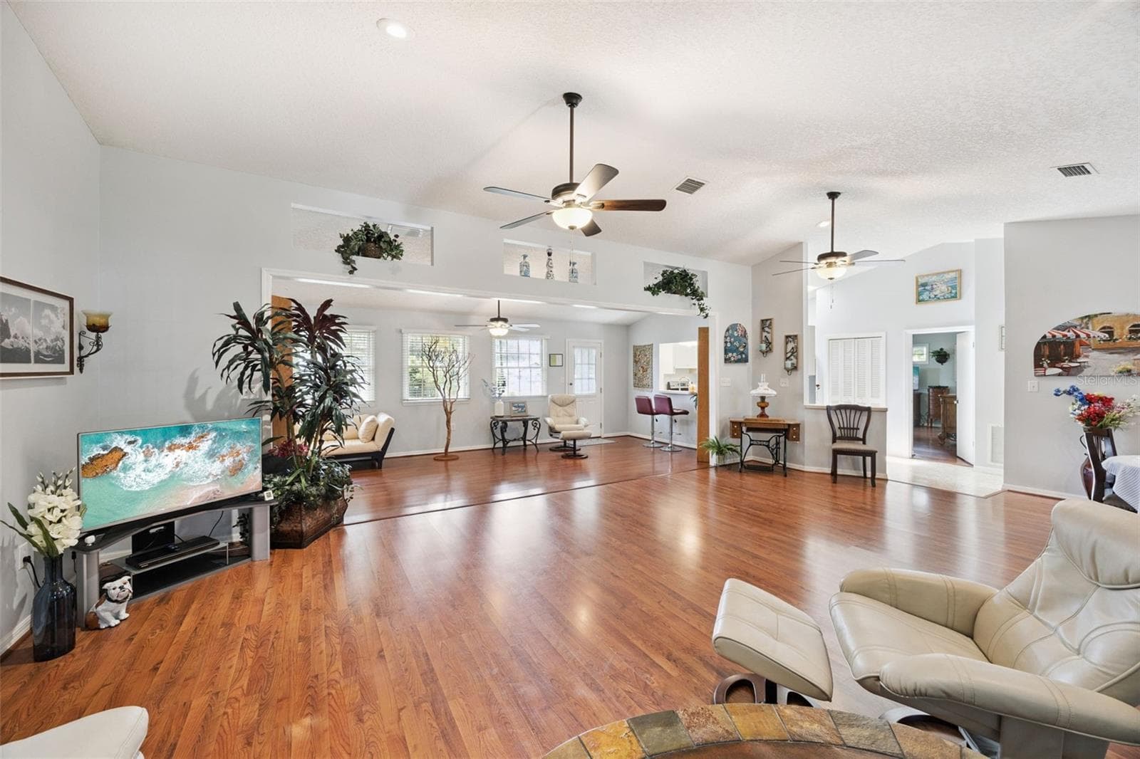 Great room view toward the family room with open sightlines, plant ledges, and continuous laminate flooring in this Mount Dora split-plan home - 480 LAKE FOREST CIR, MOUNT DORA