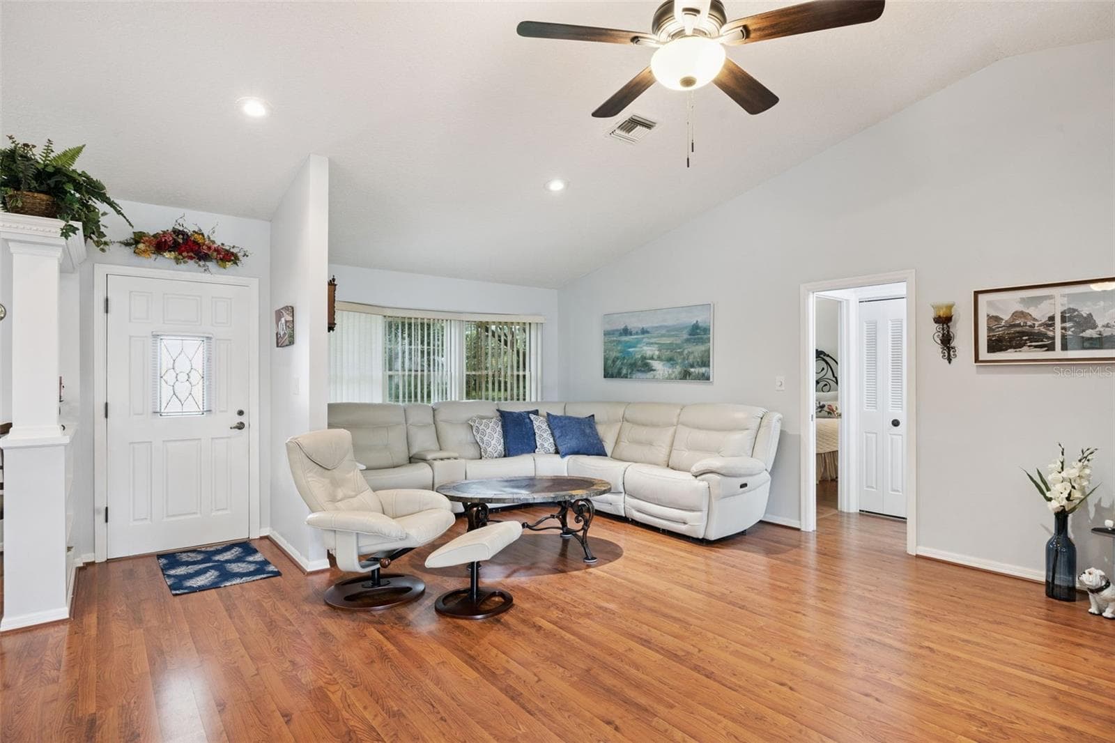 Living room looking toward the foyer entry with vaulted ceiling and laminate floors at this $380,900 Mount Dora listing - 480 LAKE FOREST CIR, MOUNT DORA
