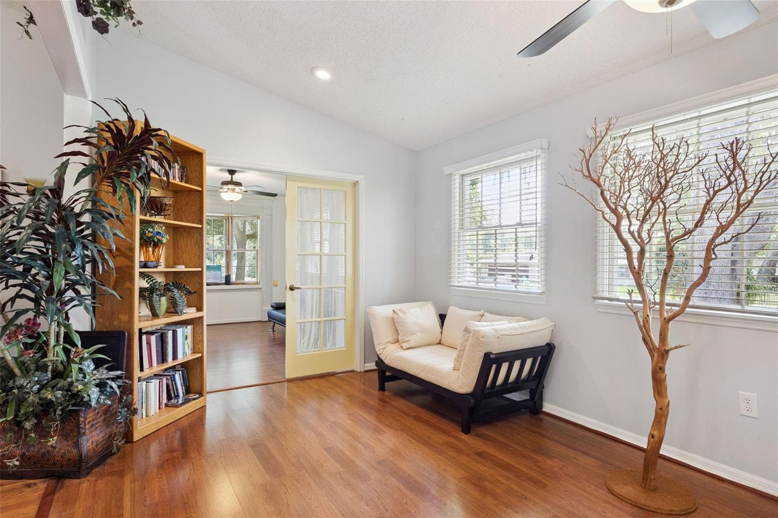 Family room sitting area with backyard views through multiple windows and ceiling fan at this 3-bed/2-bath home priced at $199/sq ft - 480 LAKE FOREST CIR, MOUNT DORA