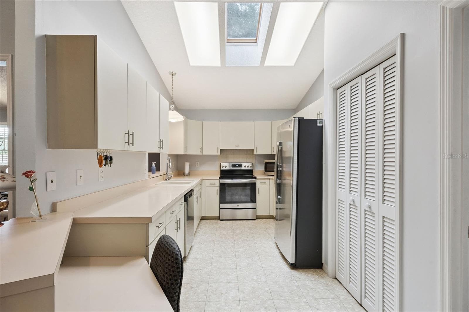Kitchen with skylights, range, refrigerator, and ample cabinetry at this split-plan Mount Dora home in Lake Forest - 480 LAKE FOREST CIR, MOUNT DORA