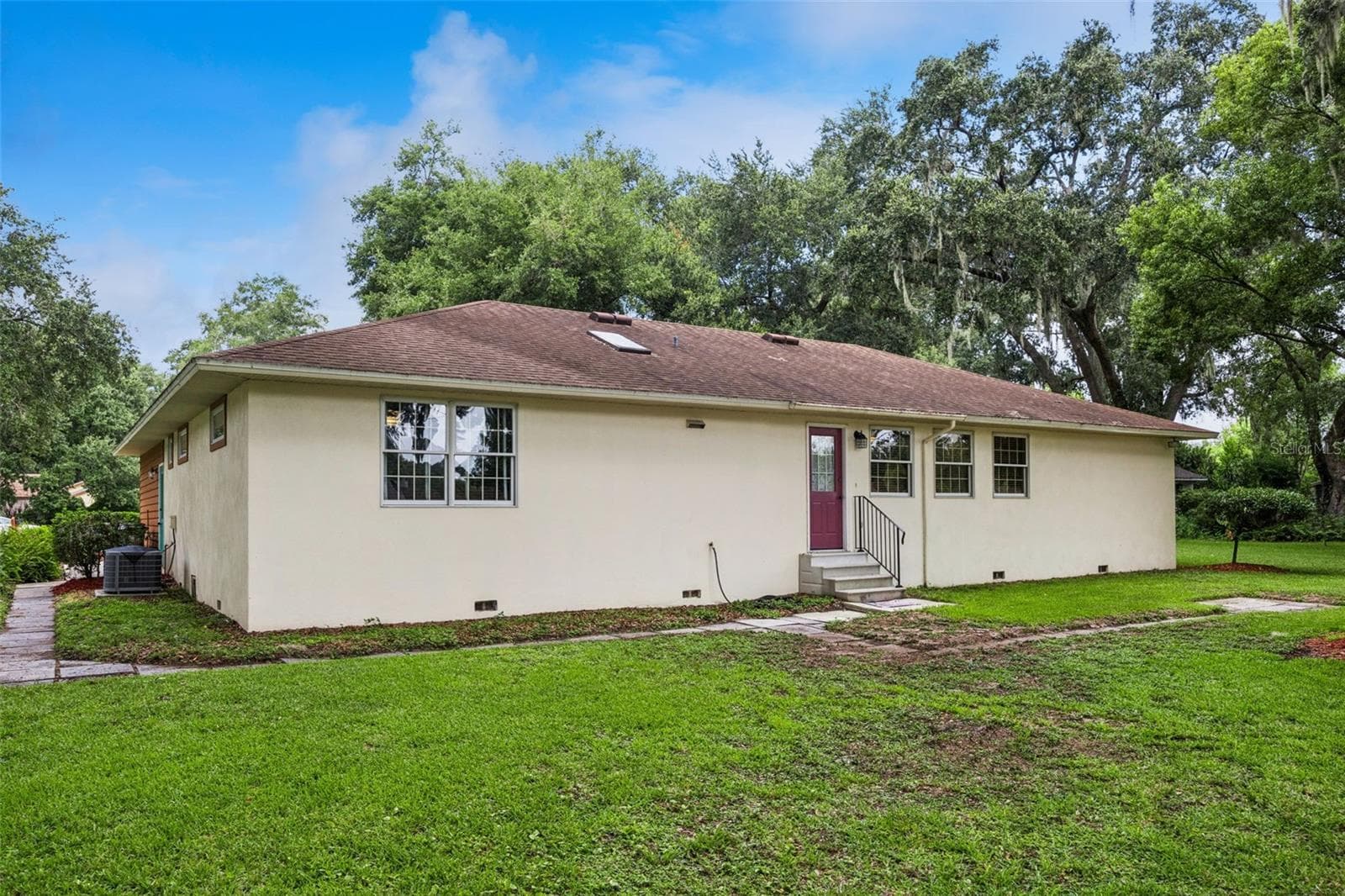 Rear exterior showing stucco construction and walkway to the backyard at this 0.46-acre Mount Dora property - 480 LAKE FOREST CIR, MOUNT DORA