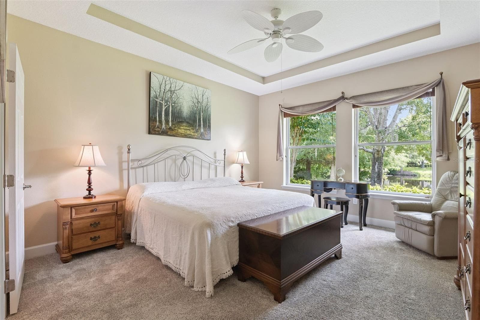 13'6" x 14'9" Primary Bedroom w/ a tray ceiling, ceiling fan & a Pond view - 1381 ABBOT WAY, DELAND