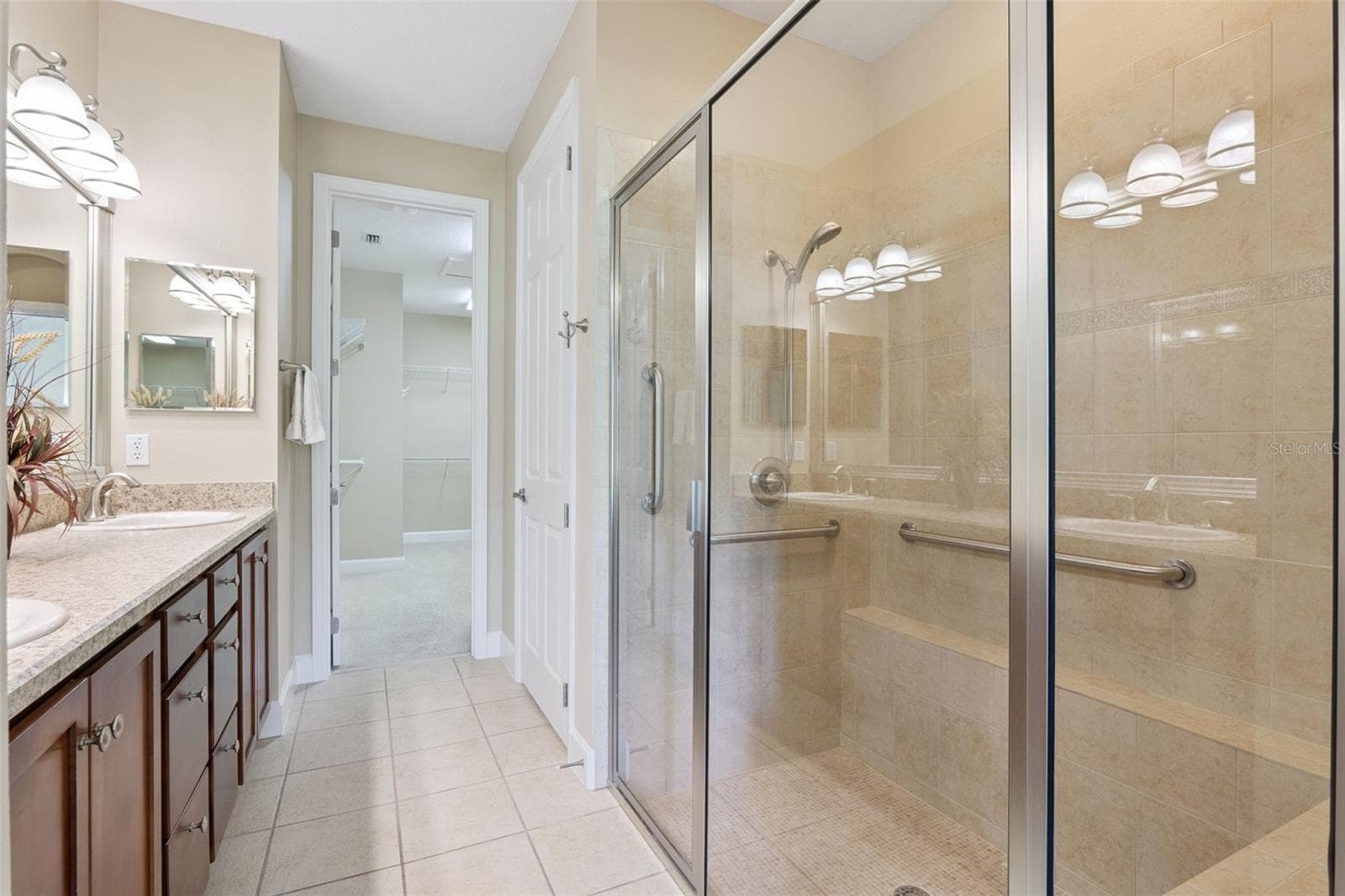 Primary Bathroom w/ a glass enclosed walk-in shower, bench seat, grab bars & a vanity w/ dual sinks - 1381 ABBOT WAY, DELAND
