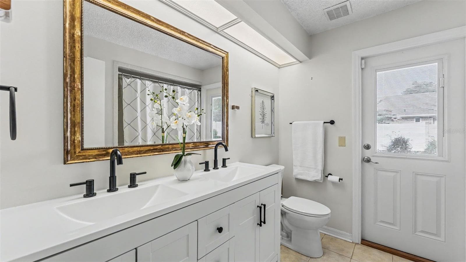 hall bathroom with new double vanity and door out to the paver patio - 4765 HIGHLANDS PLACE CIR, LAKELAND