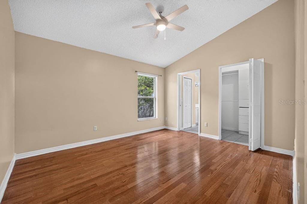 Spacious primary bedroom with vaulted ceilings and wood-look flooring. - 97 ABBEY HOLLOW DR, APOPKA