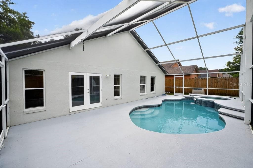 Screen-enclosed pool and spa with an expansive pool deck, an ideal for outdoor enjoyment. - 97 ABBEY HOLLOW DR, APOPKA