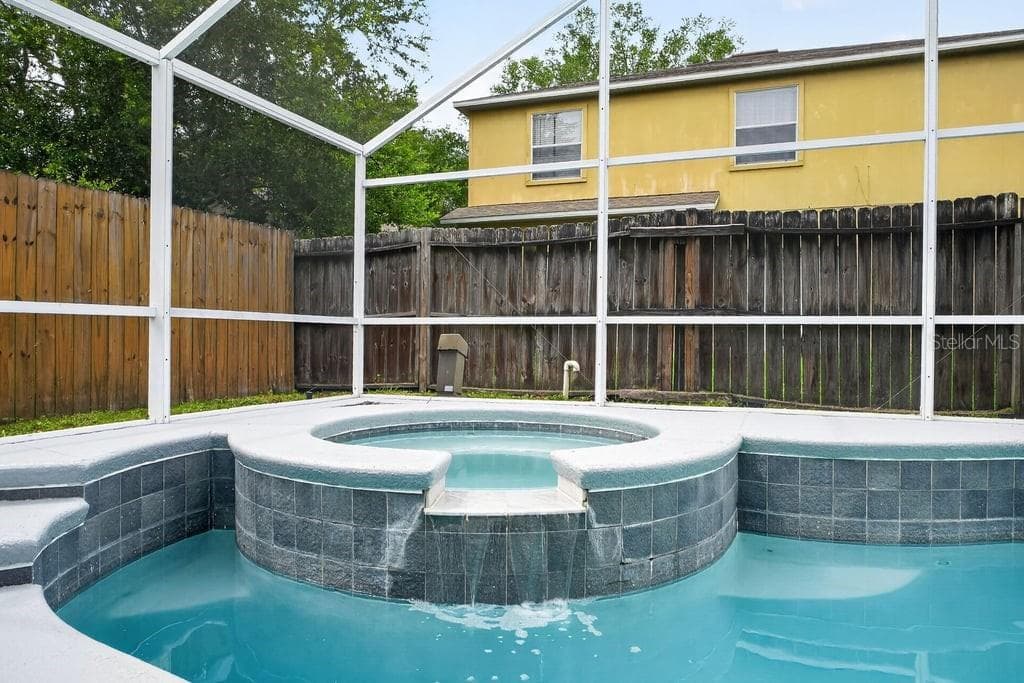 Screen -enclosed spa with spillover waterfall into the pool. - 97 ABBEY HOLLOW DR, APOPKA