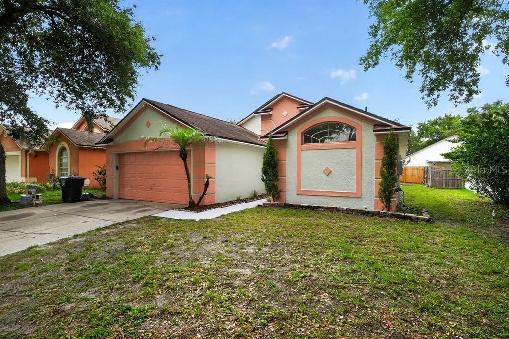 Wide view of the front elevation with an attached two-car garage. - 97 ABBEY HOLLOW DR, APOPKA
