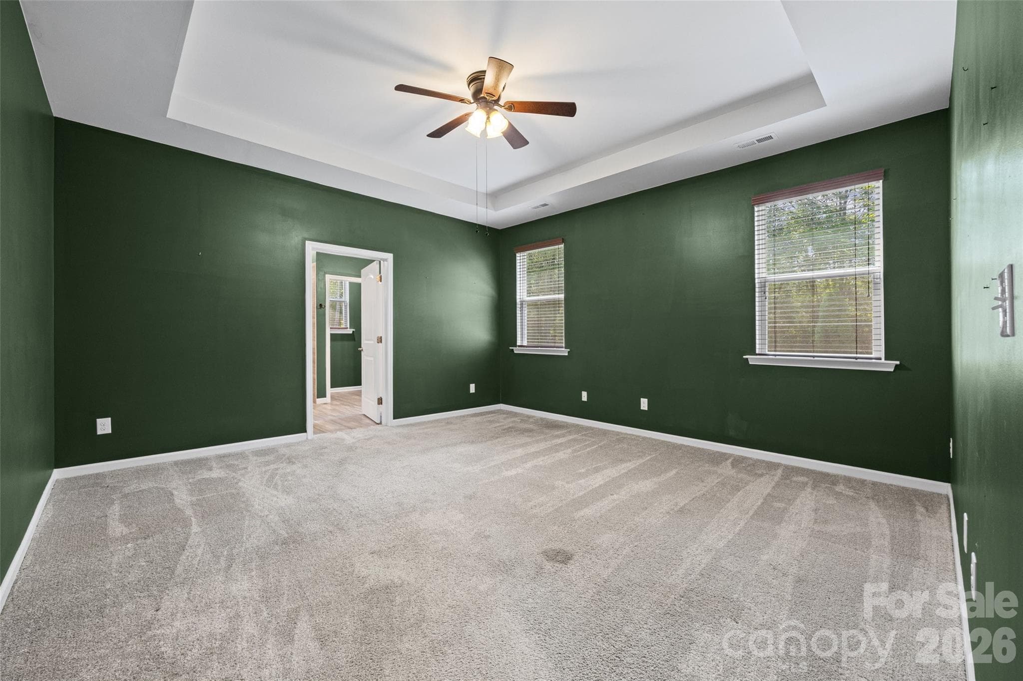 Spacious primary suite featuring a beautiful tray ceiling and ceiling fan, creating a comfortable retreat at the end of the day. - 596 Rustlewood Way, Rock Hill
