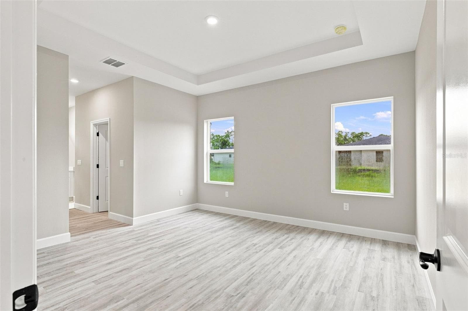 Spacious primary bedroom with tray ceiling detail. - 8211 ELKENBERRY AVE, NORTH PORT