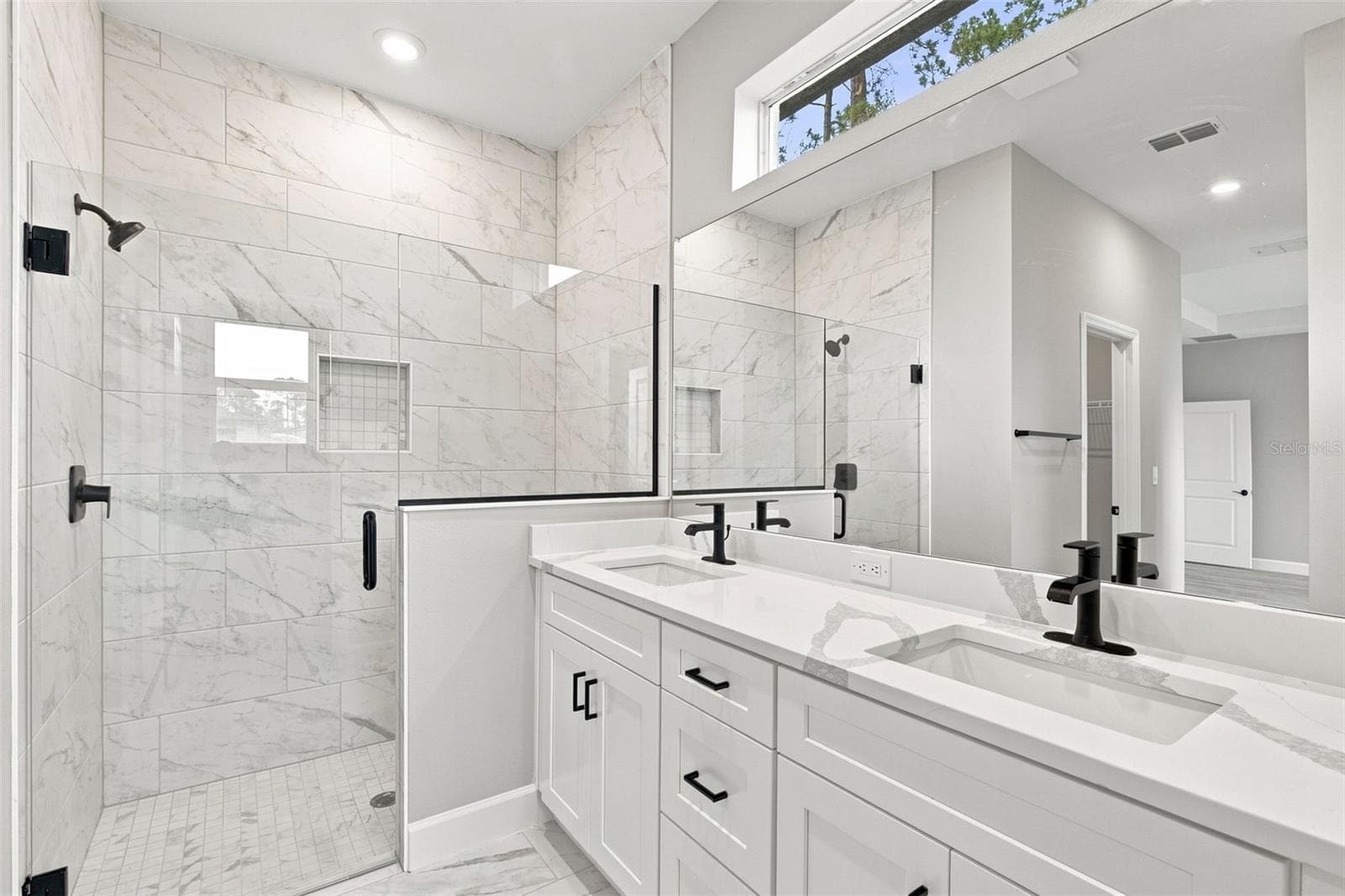 Primary ensuite bath offers timeless finishes, dual vanities and spacious walk-in tiled shower. - 8211 ELKENBERRY AVE, NORTH PORT