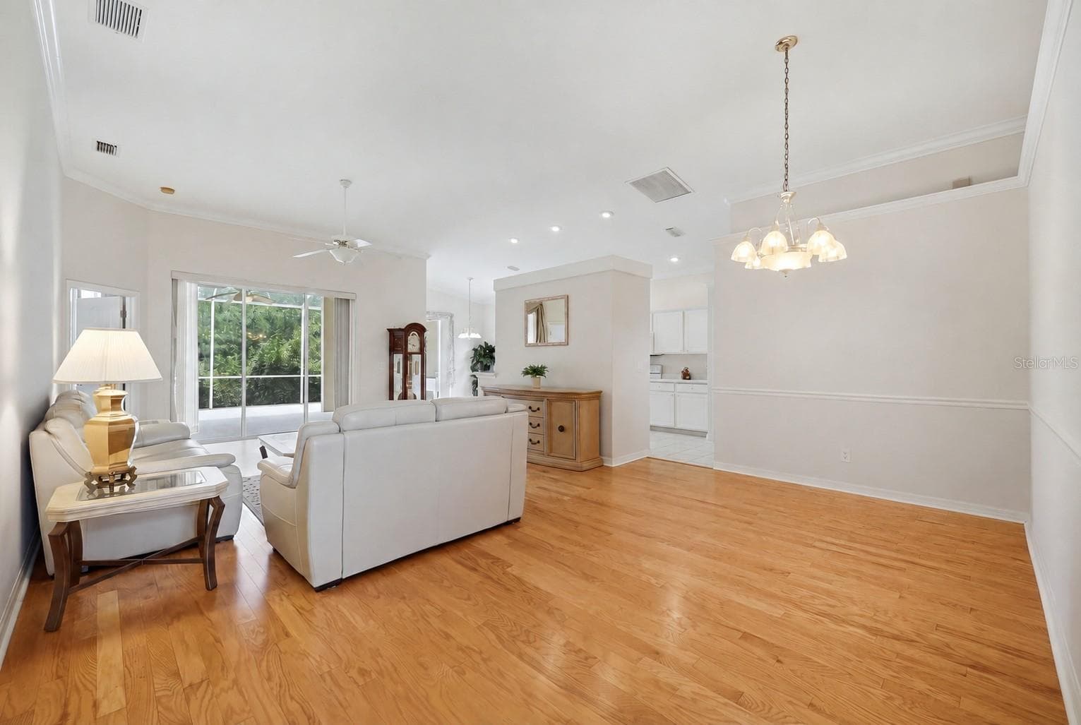 Open-concept kitchen and living area with island, hardwood floors and natural light - 8492 IDLEWOOD CT, LAKEWOOD RANCH