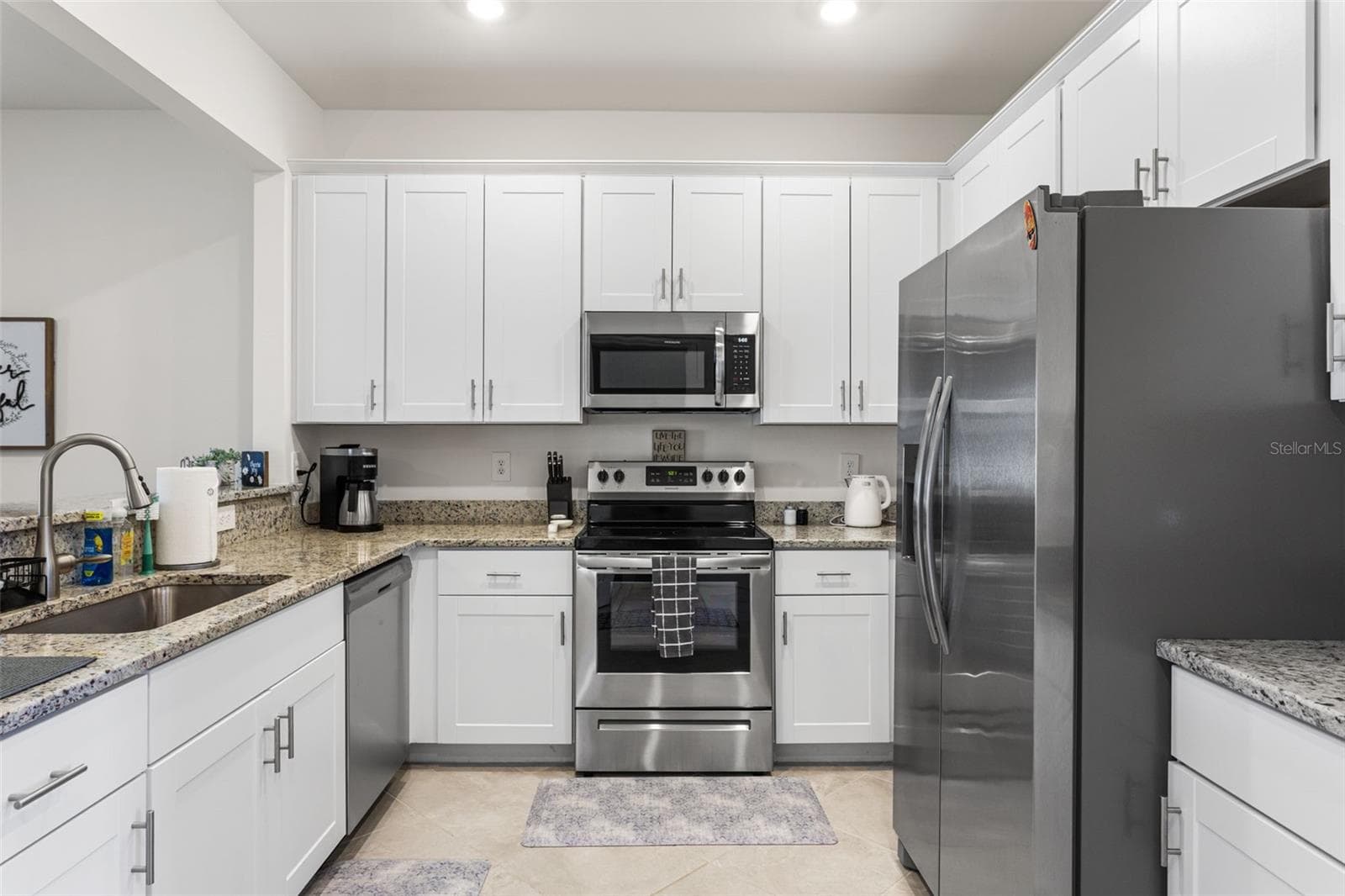 The spacious kitchen boasts granite countertops, stainless steel appliances, a deep sink, and white shaker cabinets - 14275 PINE LODGE LN, FORT MYERS