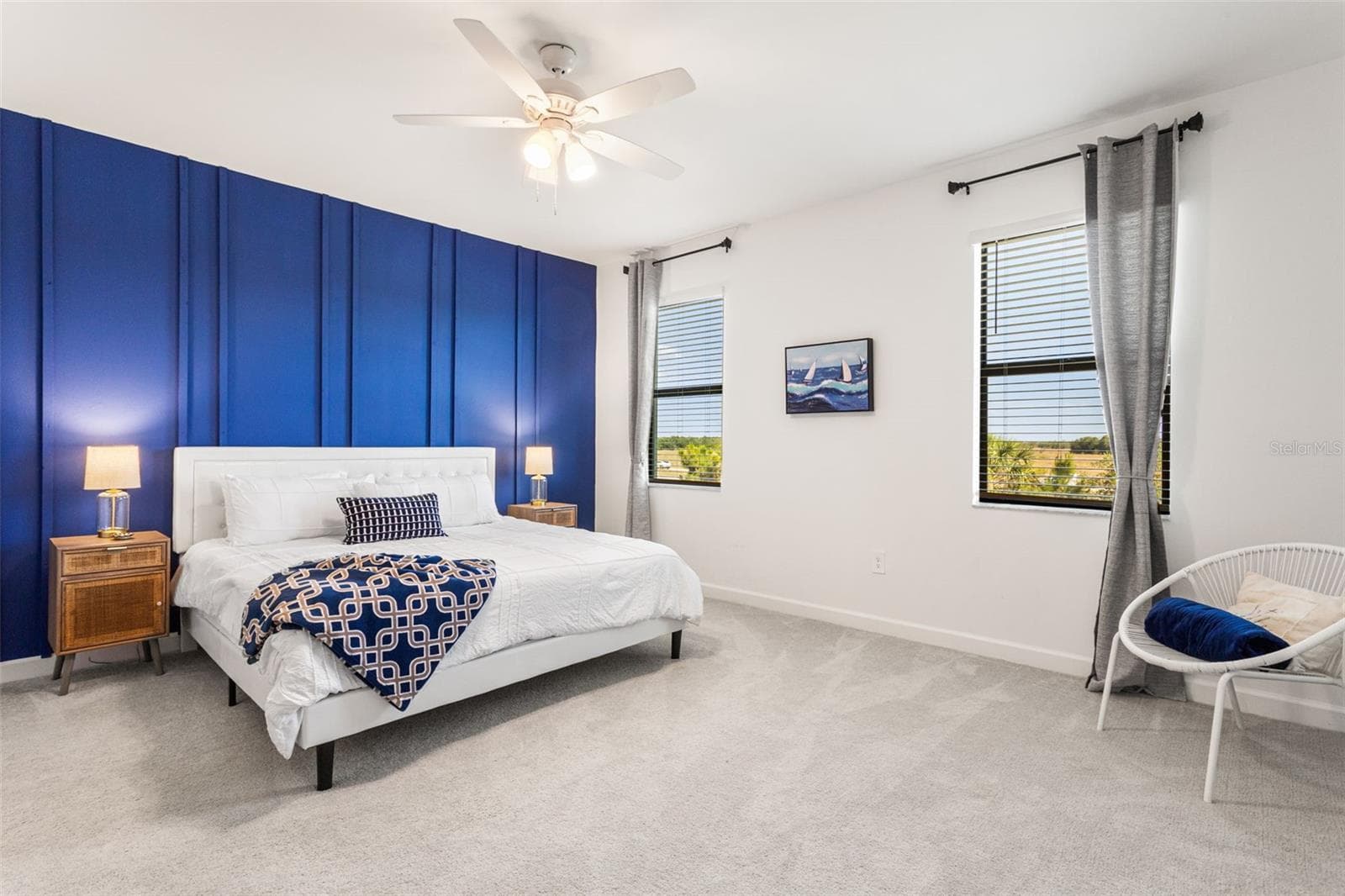 Upstairs, the carpeted second level features a large primary suite with a royal blue accent wall, dual closets, and a spacious sitting area - 14275 PINE LODGE LN, FORT MYERS