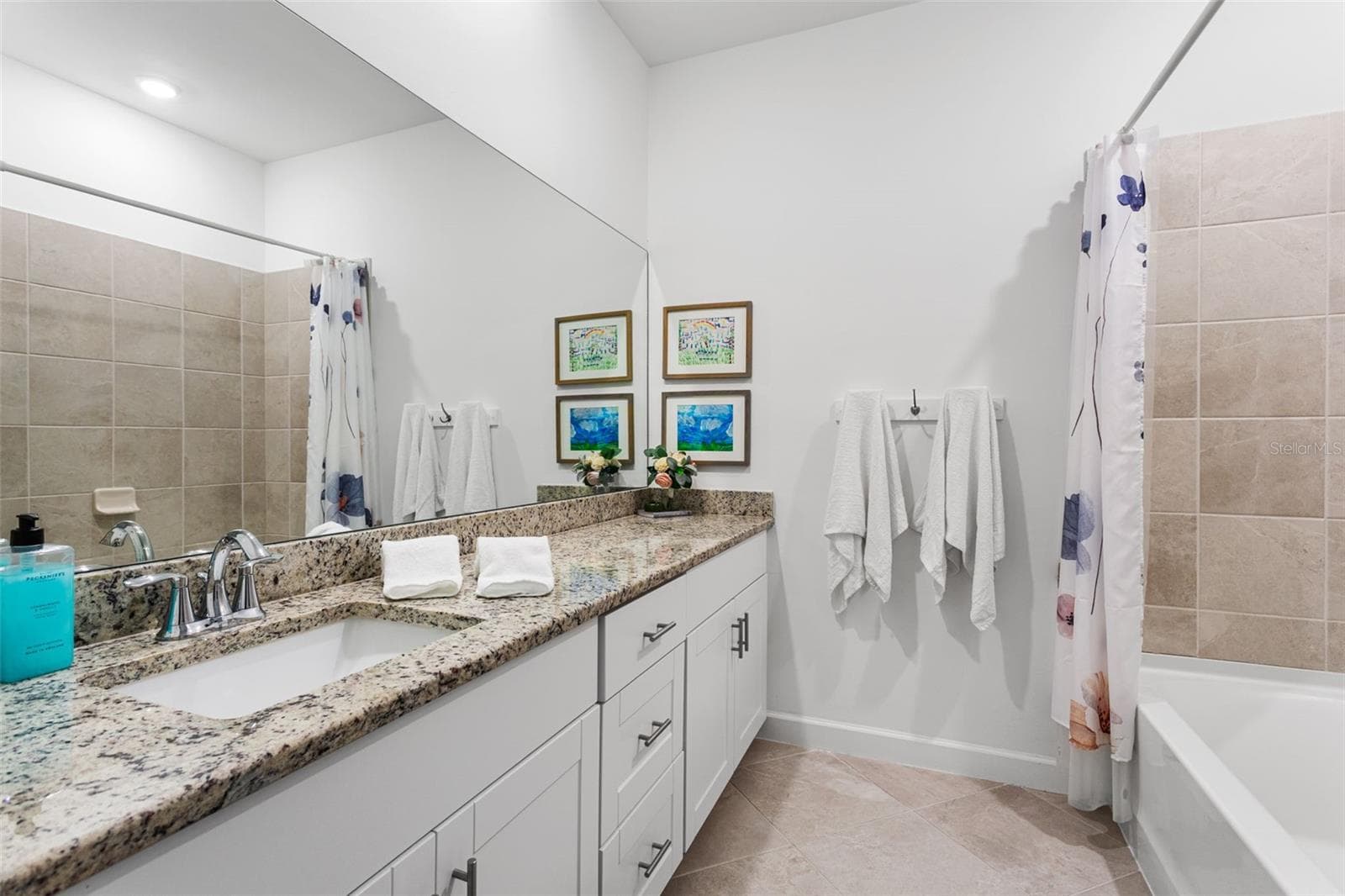 A full hallway bathroom includes a large vanity with granite countertop, tub/shower combo, and linen storage - 14275 PINE LODGE LN, FORT MYERS