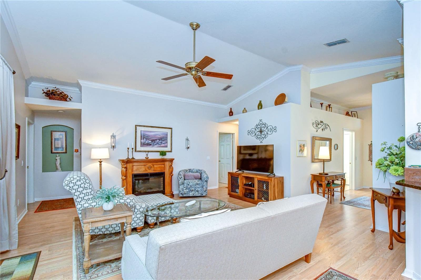 Rich wood flooring, crown molding, neutral paint, and vaulted ceilings create a warm and sophisticated atmosphere. - 5602 ROCKFIELD LOOP, VALRICO