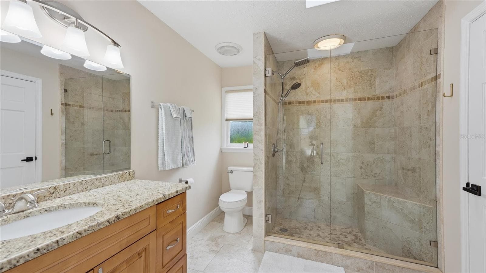 Bathroom 3 features walk-in shower with seamless glass enclosure, a built-in seat and dual shower heads. - 15127 PENNINGTON RD, TAMPA