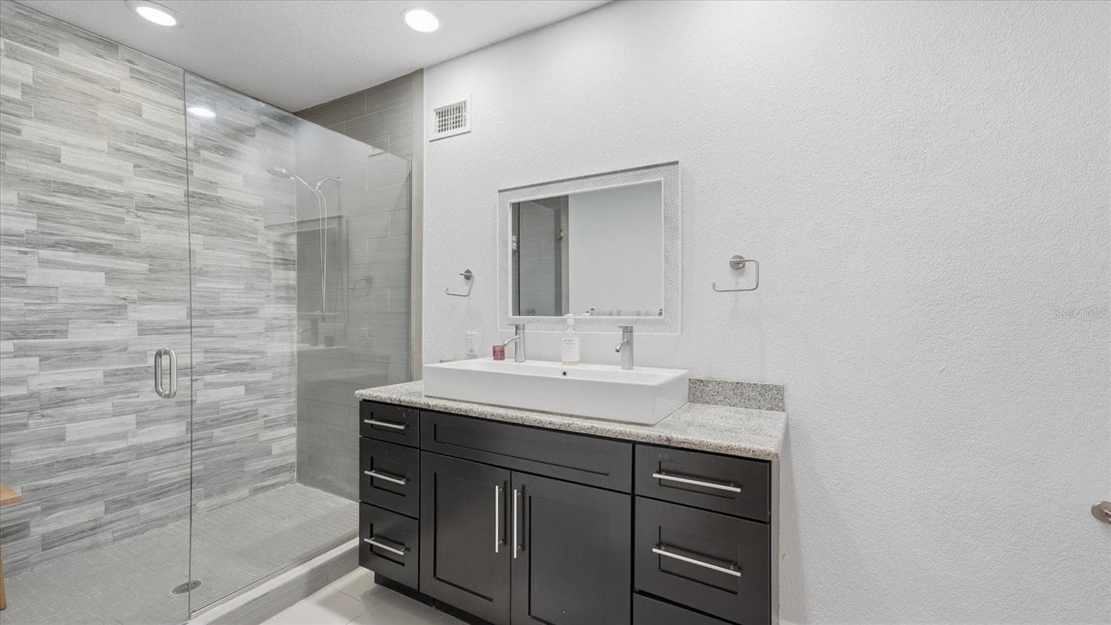 Large walk-in shower with seamless glass enclosure and spacious vanity with storage drawers and cabinet - 15127 PENNINGTON RD, TAMPA