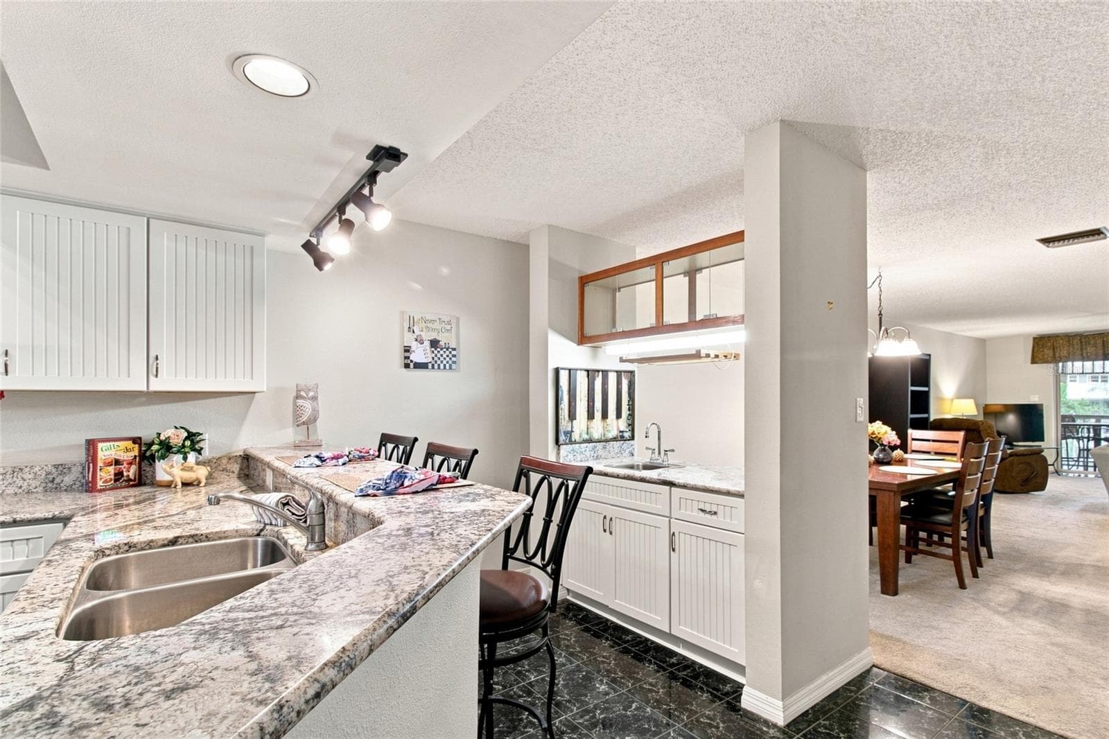 Kitchen w/ Breakfast Bar Stools and wet bar into sppacious dining room - 2599 DOLLY BAY DR #306, PALM HARBOR