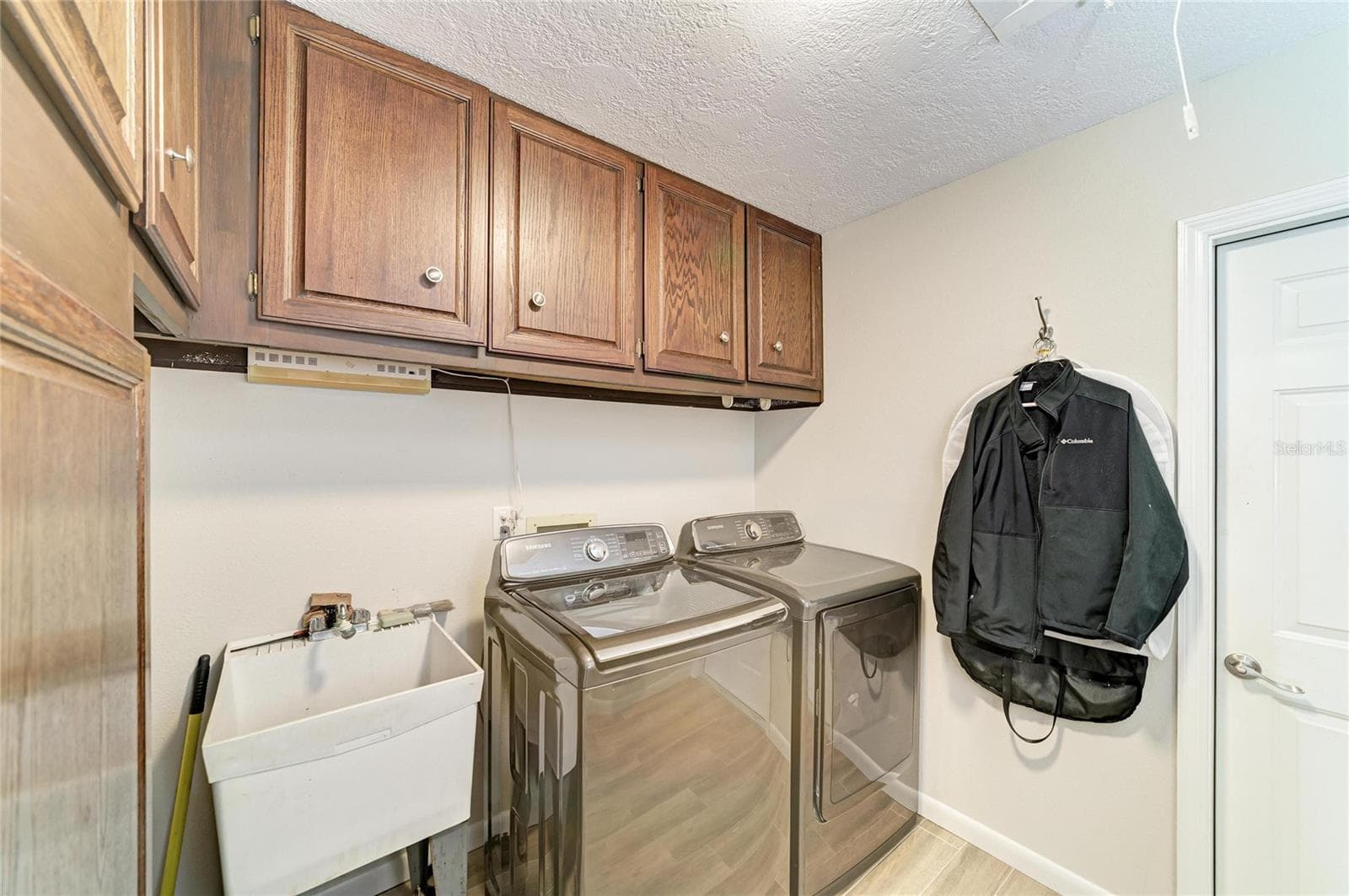 Spacious indoor laundry room with utility sink and storage cabinets. - 2011 37TH ST W, BRADENTON