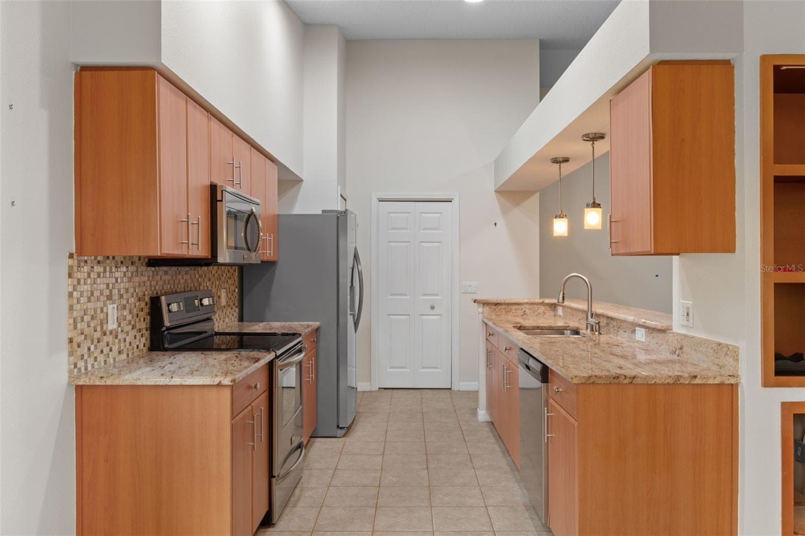 kitchen with granite counter tops and tile floor overlooking living area with bar - 18055 TARRINGTON PL, HUDSON