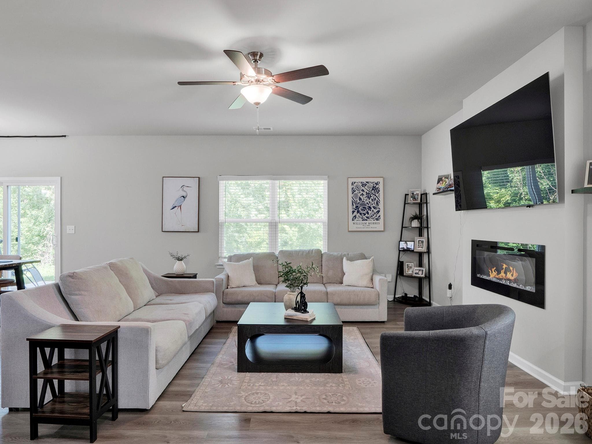Fireplace flanking generous living room with large windows looking out on mature trees. - 7203 Stoney Wood Lane, Charlotte