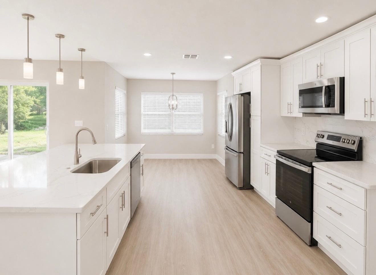 Full redesigned Kitchen is open to Living Room with brand new 42" cabinets, quartz countertops, enormous center island with double sided cabinets, marble tile backsplash, new stainless steel appliances and breakfast nook. - 10814 CRESCENDO LOOP, CLERMONT