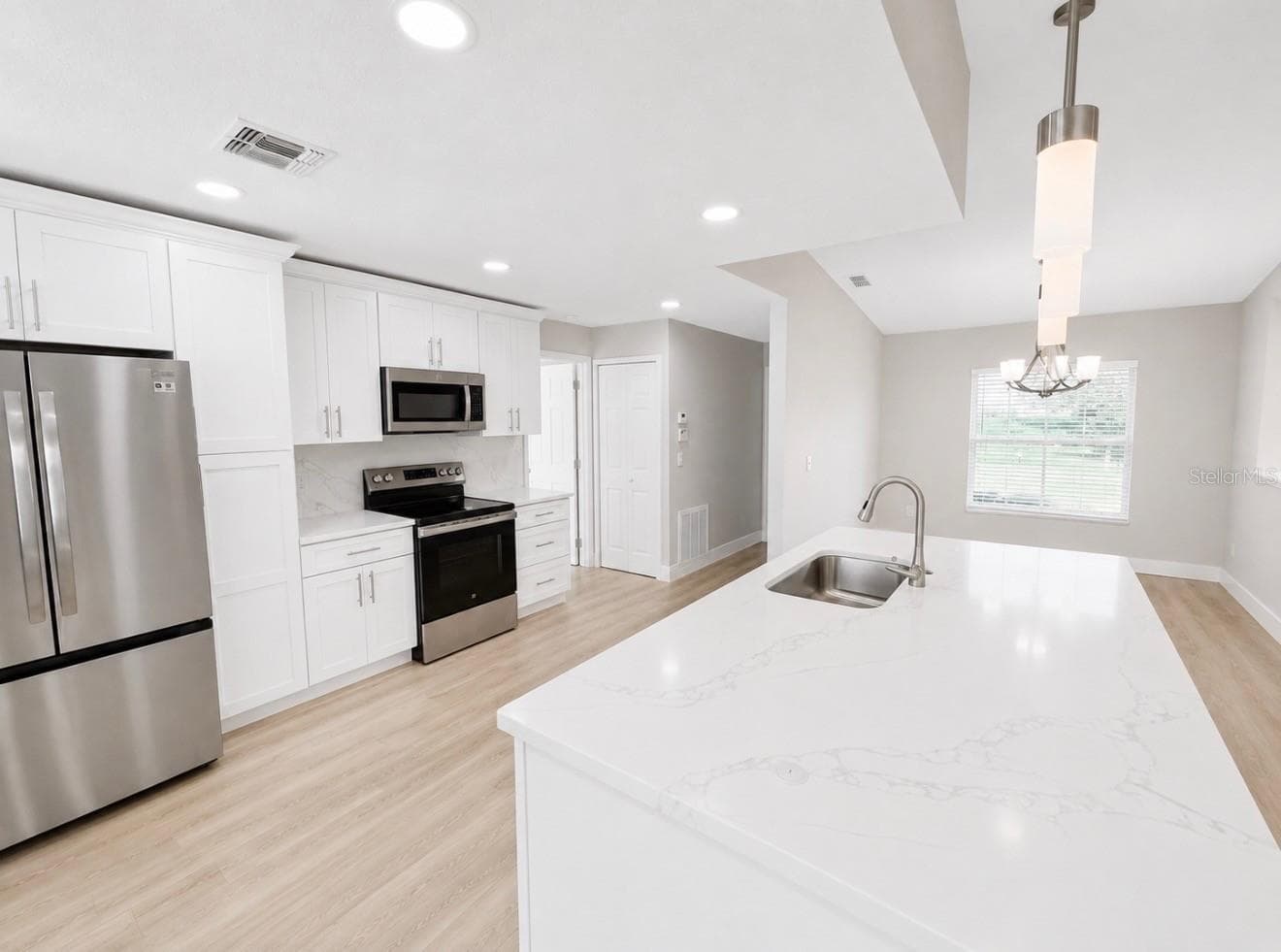 Full redesigned Kitchen is open to Living Room with brand new 42" cabinets, quartz countertops, enormous center island with double sided cabinets, marble tile backsplash, new stainless steel appliances and breakfast nook. - 10814 CRESCENDO LOOP, CLERMONT