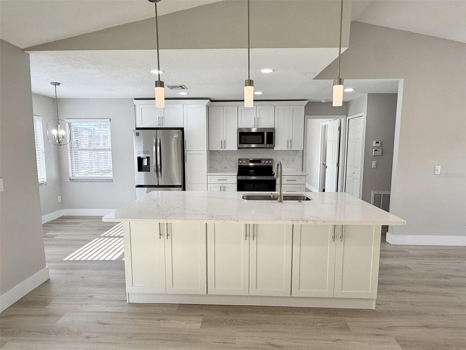 Full redesigned Kitchen is open to Living Room with brand new 42" cabinets, quartz countertops, enormous center island with double sided cabinets, marble tile backsplash, new stainless steel appliances and breakfast nook. - 10814 CRESCENDO LOOP, CLERMONT