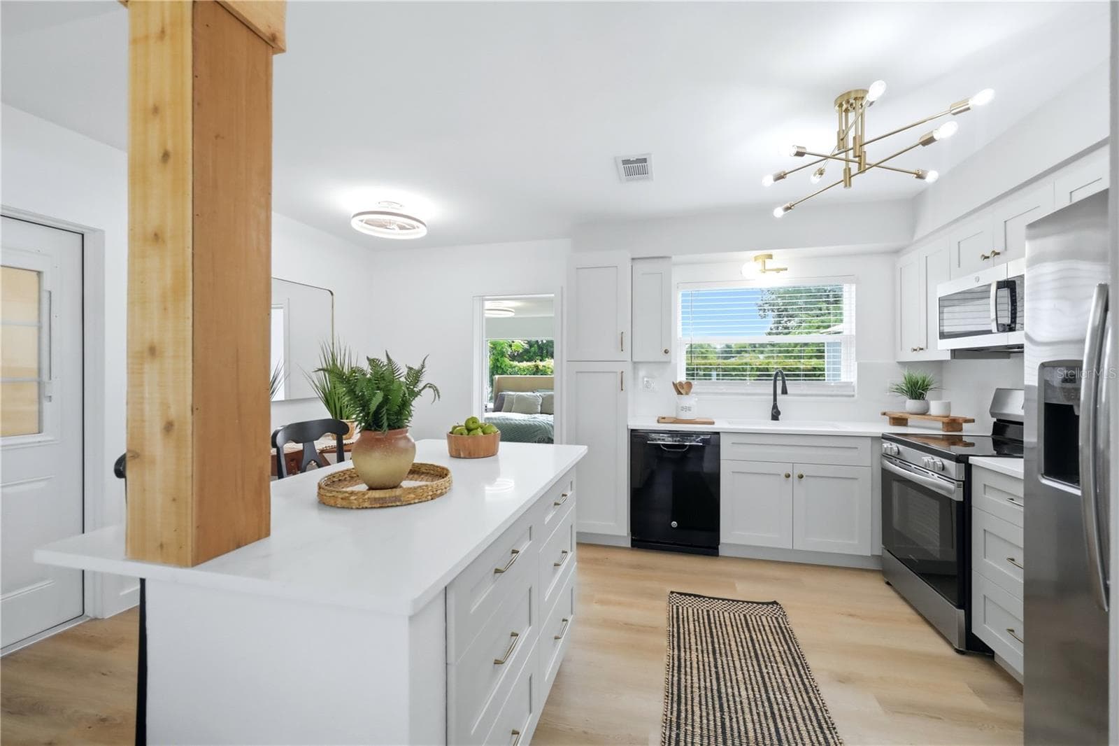 Renovated kitchen with oversized island, white cabinetry and stainless steel appliances - 6103 CARLTON AVE, SARASOTA