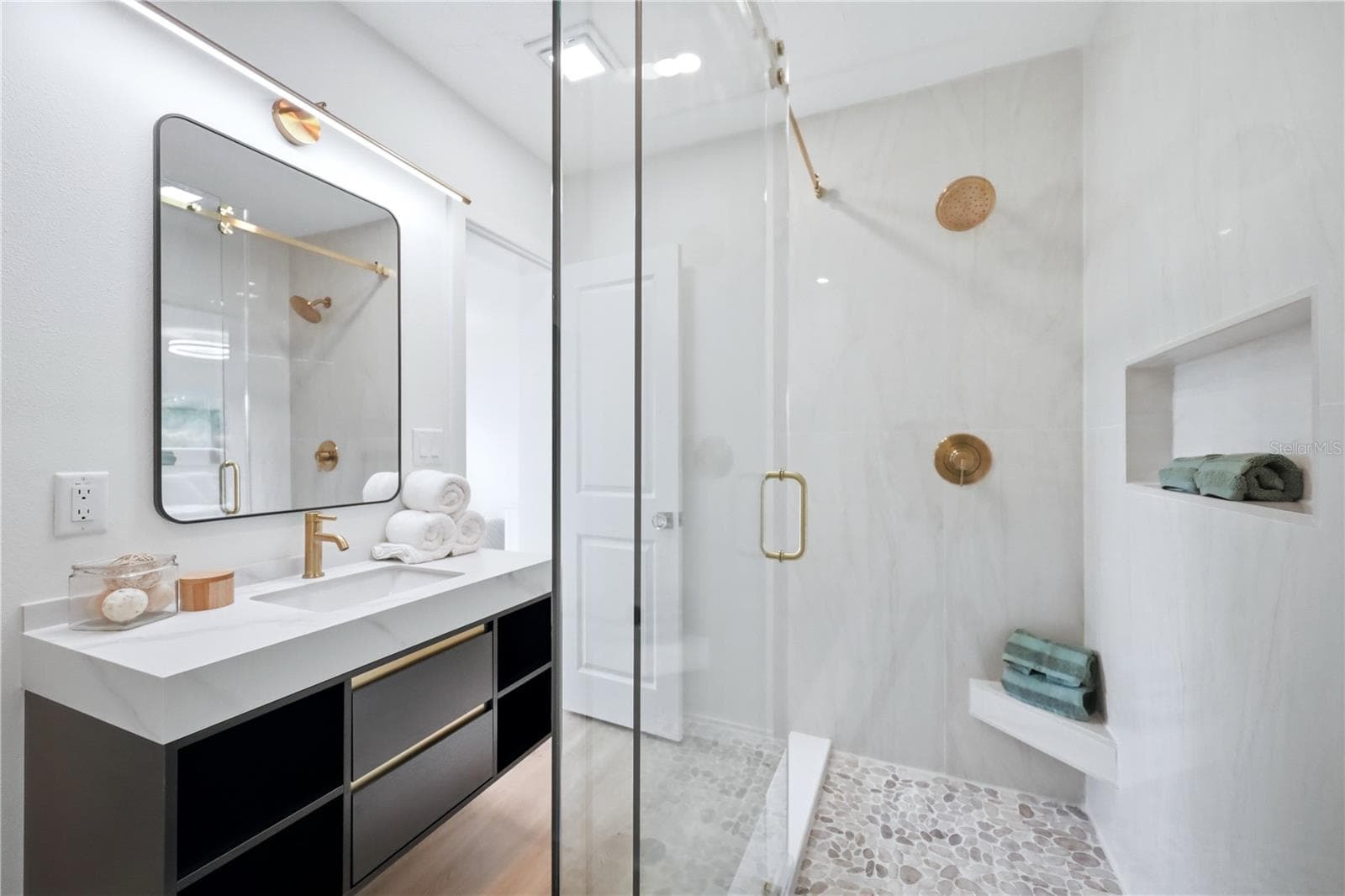 Renovated primary bathroom with walk-in closet, modern vanity, tile shower and hidden closet. - 6103 CARLTON AVE, SARASOTA