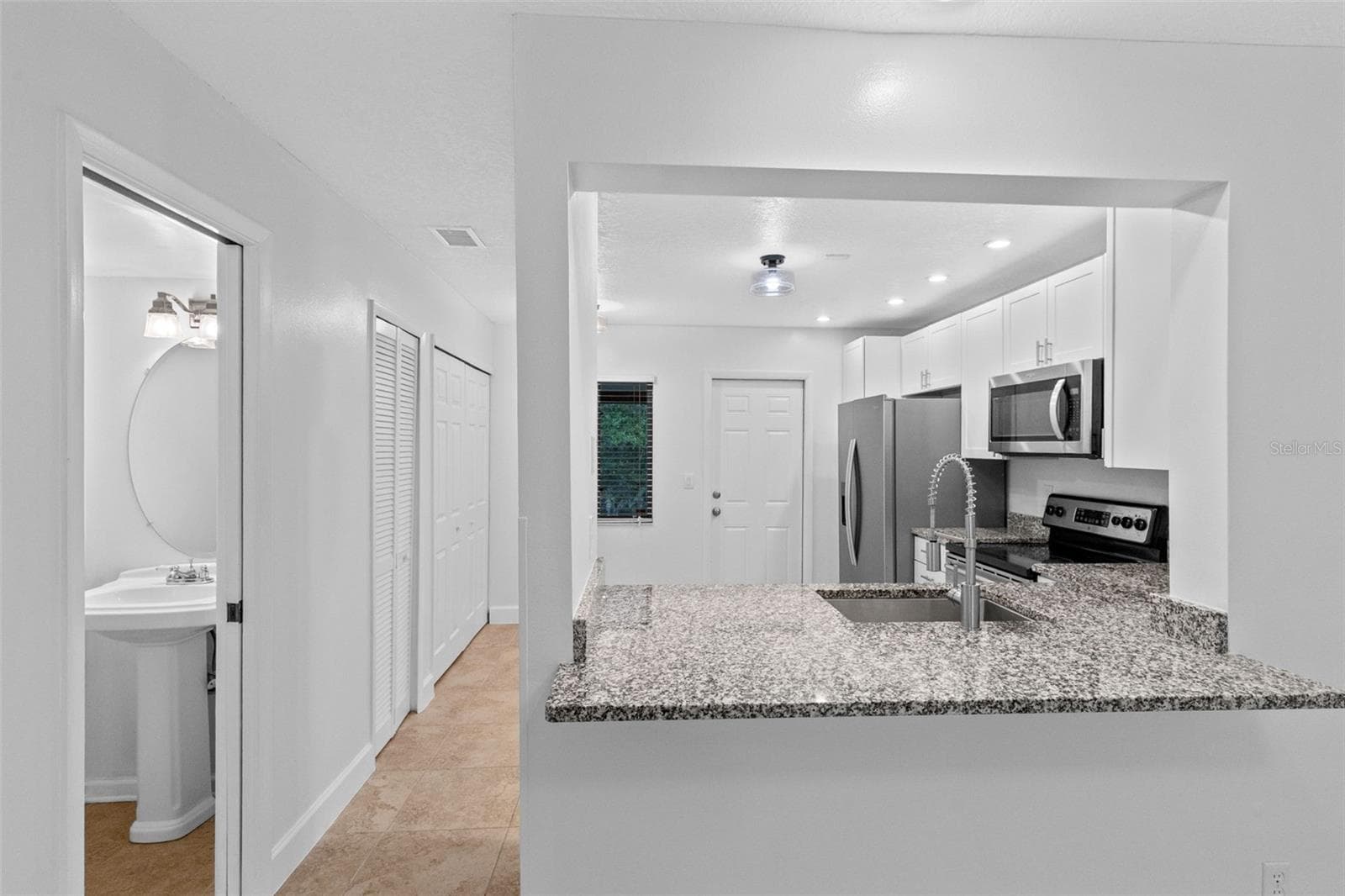 The updated kitchen features white cabinetry, granite countertops, stainless steel appliances and a breakfast bar overlooking the living and dining space. - 283 SANDLEWOOD TRL #3, WINTER PARK