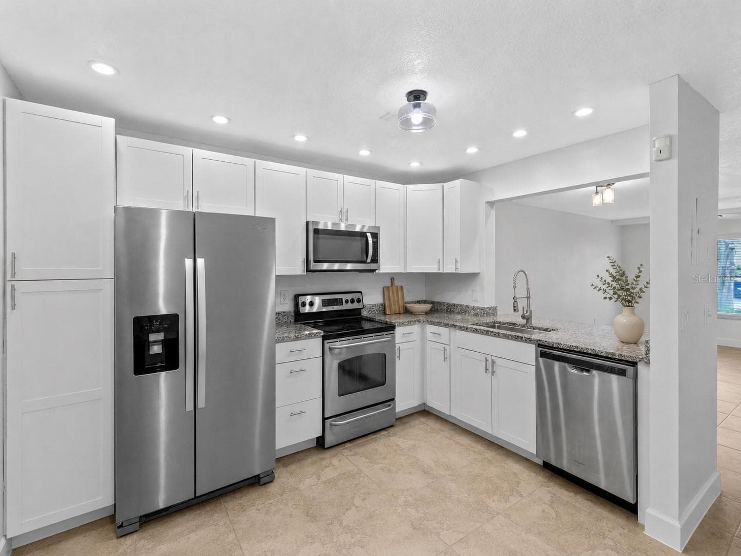 The updated kitchen features white cabinetry, granite countertops, stainless steel appliances and a breakfast bar overlooking the living and dining space. - 283 SANDLEWOOD TRL #3, WINTER PARK