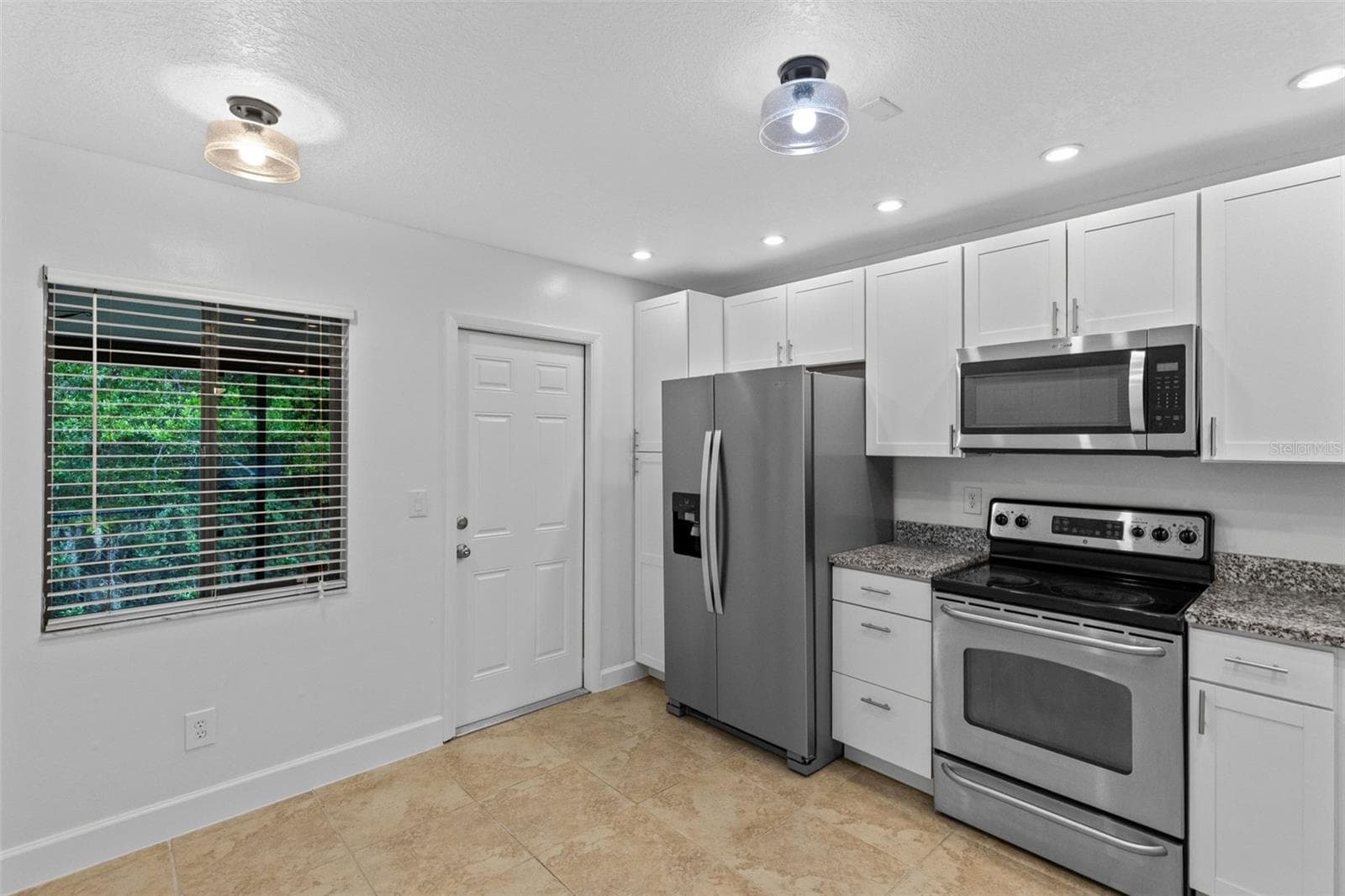 The updated kitchen features white cabinetry, granite countertops, stainless steel appliances and a breakfast bar overlooking the living and dining space. - 283 SANDLEWOOD TRL #3, WINTER PARK