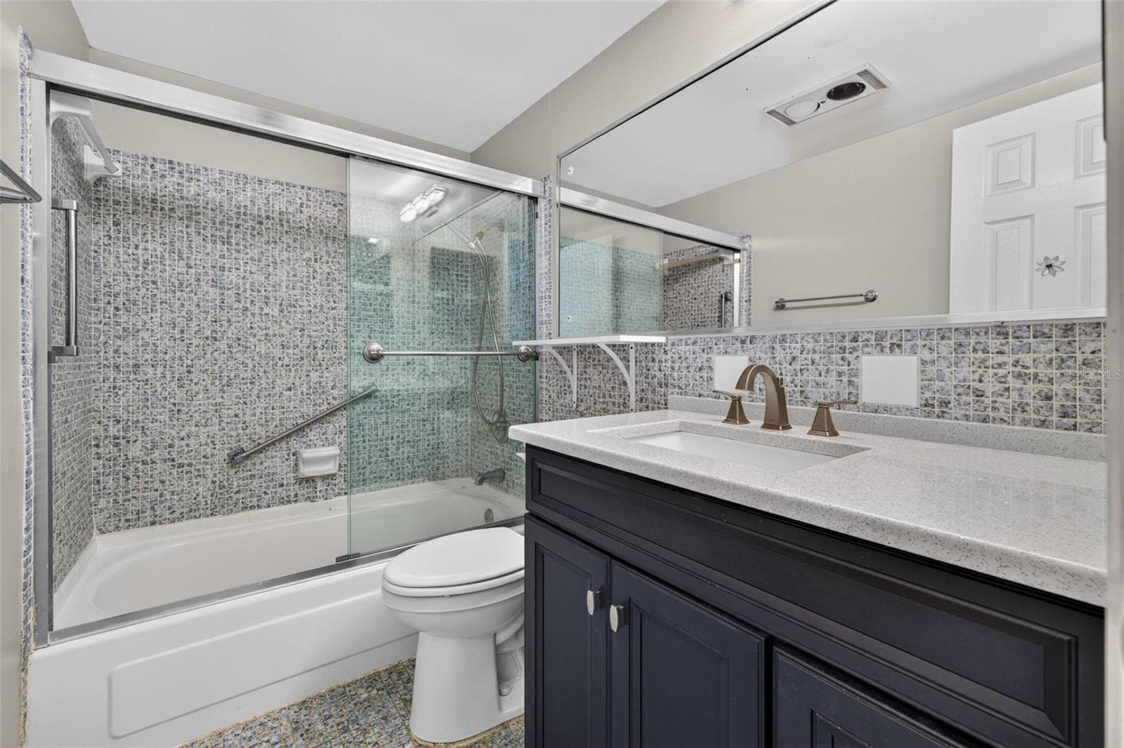 Modern full bath with a updated vanity, glass shower doors, and elegant tile finishes. - 6015 19TH ST N #215, ST PETERSBURG