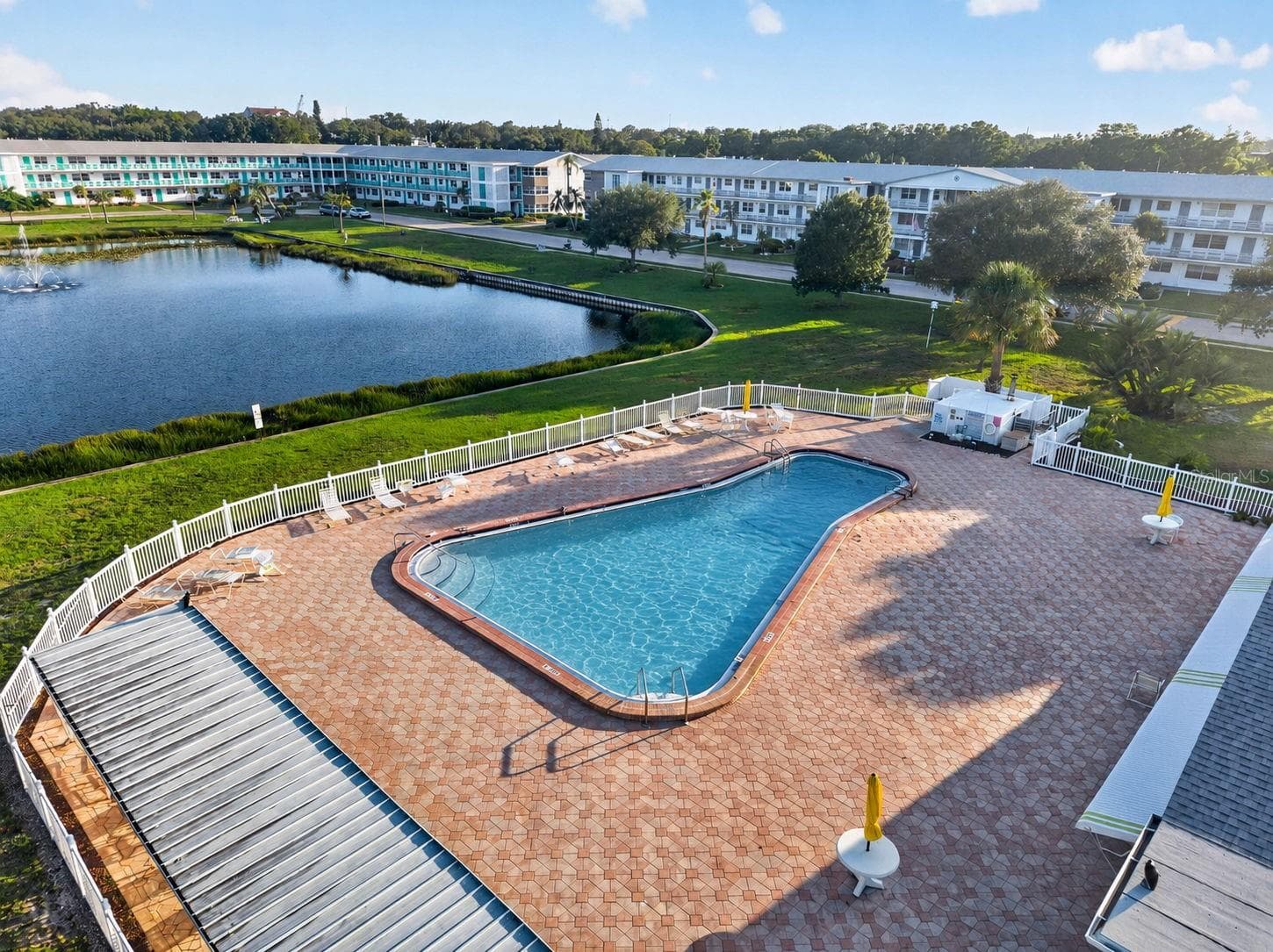 Resort-style community pool overlooking a scenic pond with a fountain. - 6015 19TH ST N #215, ST PETERSBURG