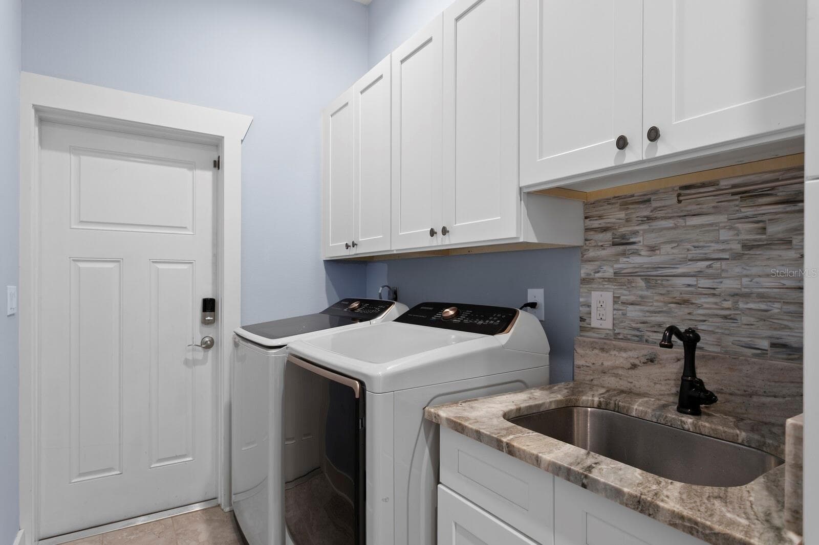 Utility room with large cabinets and utility sink leads to oversized 3-car garage - 704 EAGLE LN, APOLLO BEACH