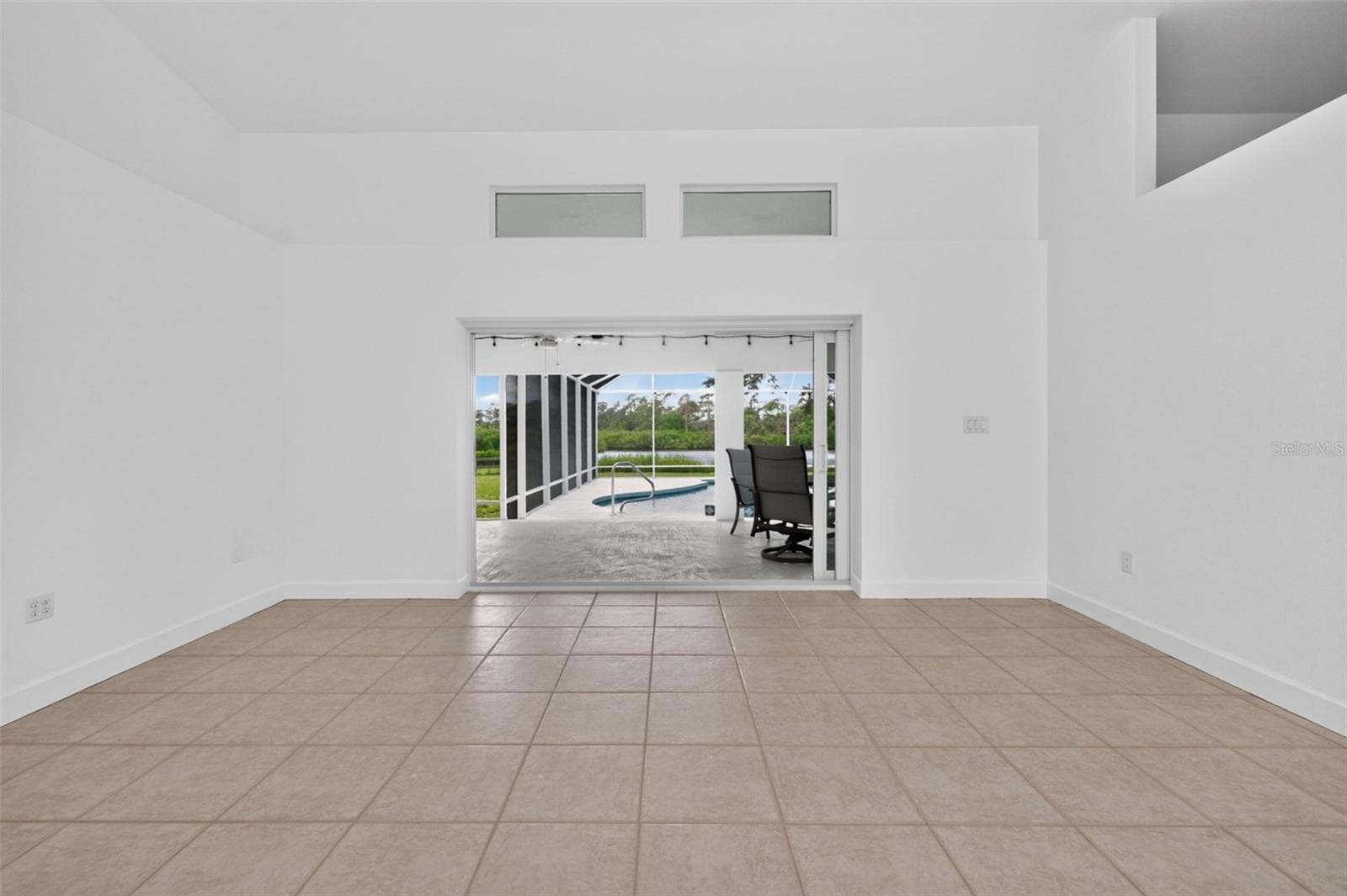 Living room has a cathedral ceiling, impact sliding glass doors to the lanai, and transom windows to let in that Florida sunshine! - 200 S OXFORD DR, ENGLEWOOD