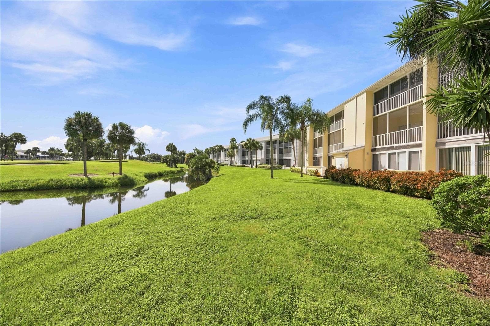 Waterside exterior showcases lush lawns, mature palms and the peaceful setting surrounding the building. - 406 CERROMAR CIR N #328, VENICE