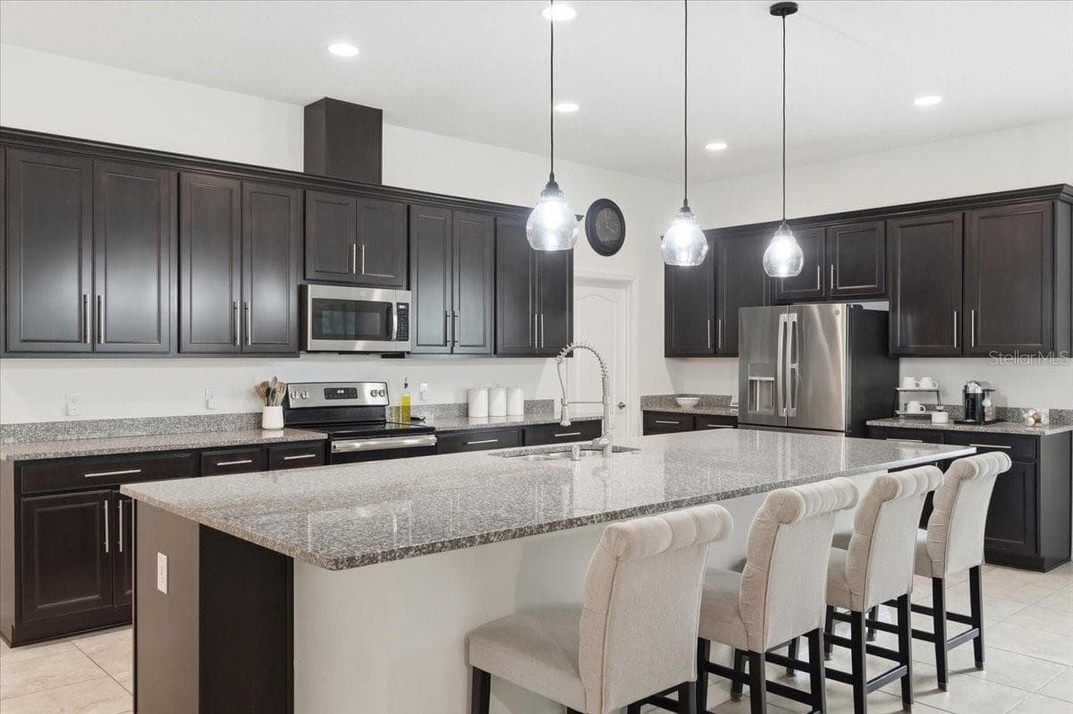 A sleek modern kitchen anchored by a massive island creates a stunning centerpiece for everything from morning coffee to unforgettable gatherings. - 4791 RIVERWALK DR, ST CLOUD