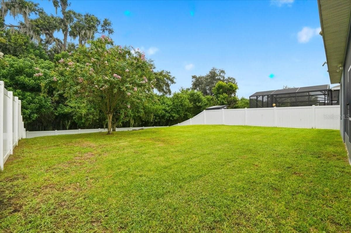 An expansive, fully fenced backyard framed by conservation offers incredible room to play, entertain or simply unwind, complete with a mature mango tree for a touch of Florida charm. - 4791 RIVERWALK DR, ST CLOUD